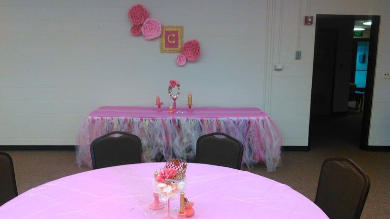 Room decorated in pink with tables, chairs, and wall decor; likely a party setting.