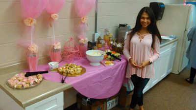 Woman in pink top at a decorated party table with food and balloons.