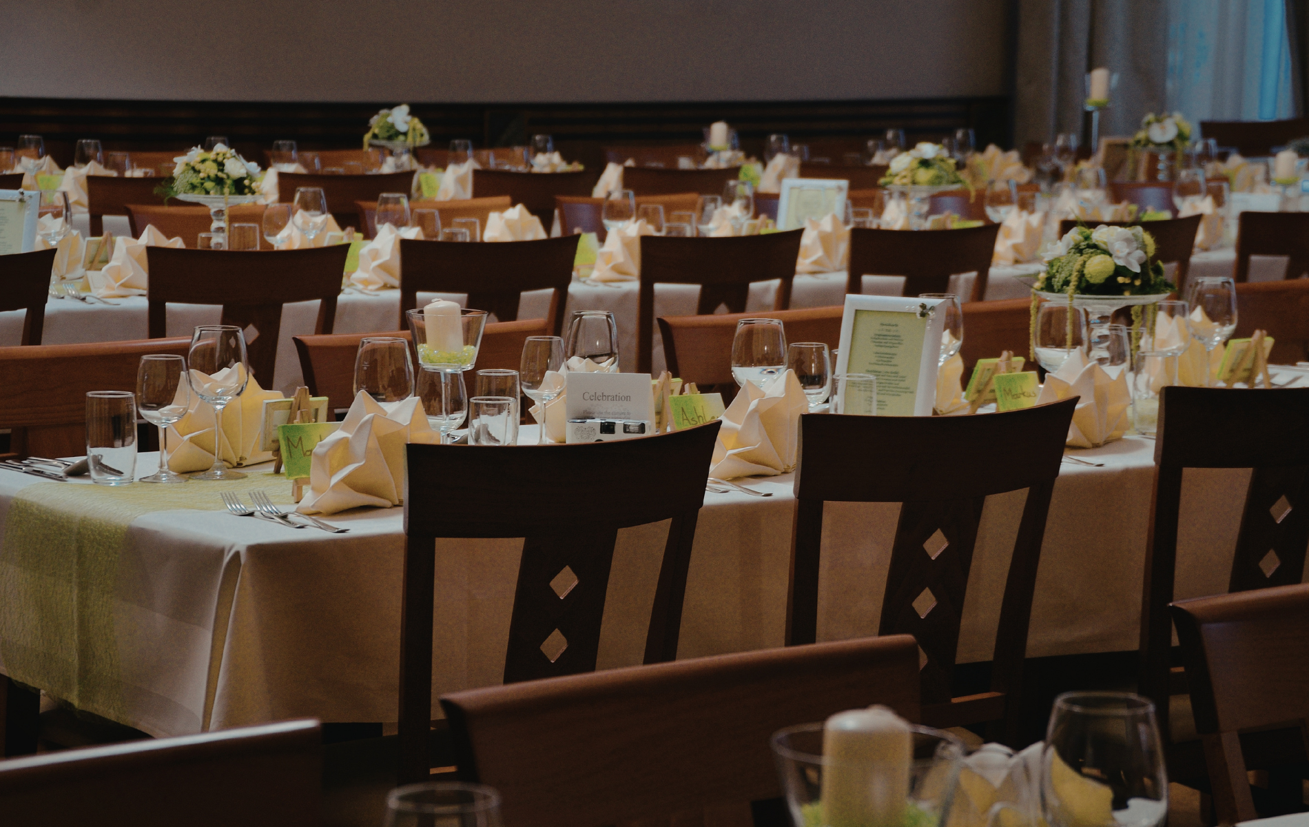 Formal banquet hall set for a large event, with many tables, chairs, and centerpieces.