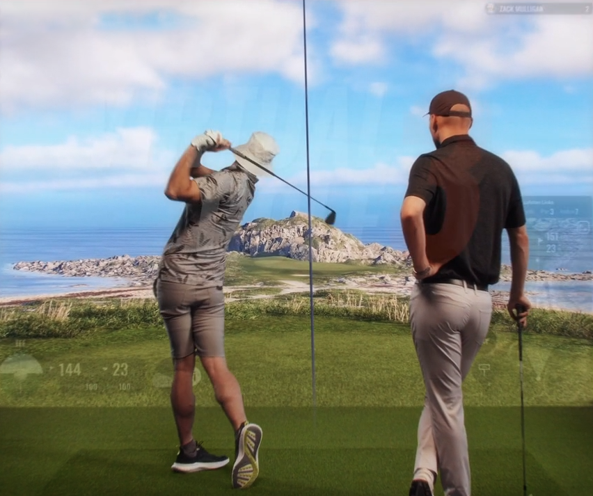 Two golfers playing an indoor virtual round on TrackMan golf simulator