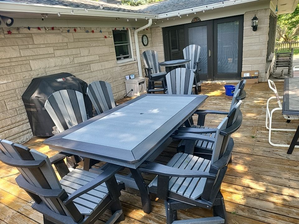 There is a table and chairs on the deck of a house.