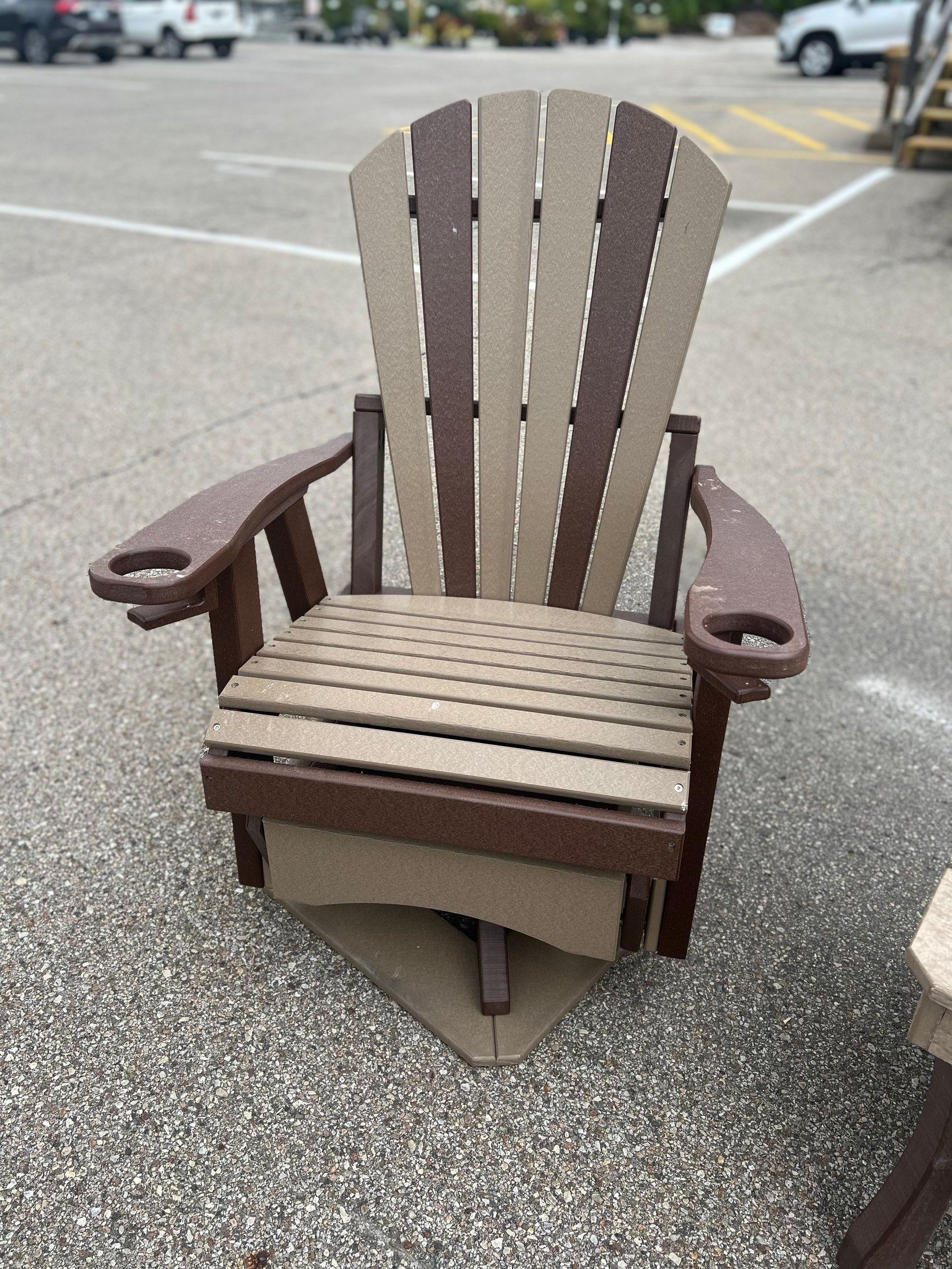 A brown and tan adirondack chair is sitting in a parking lot