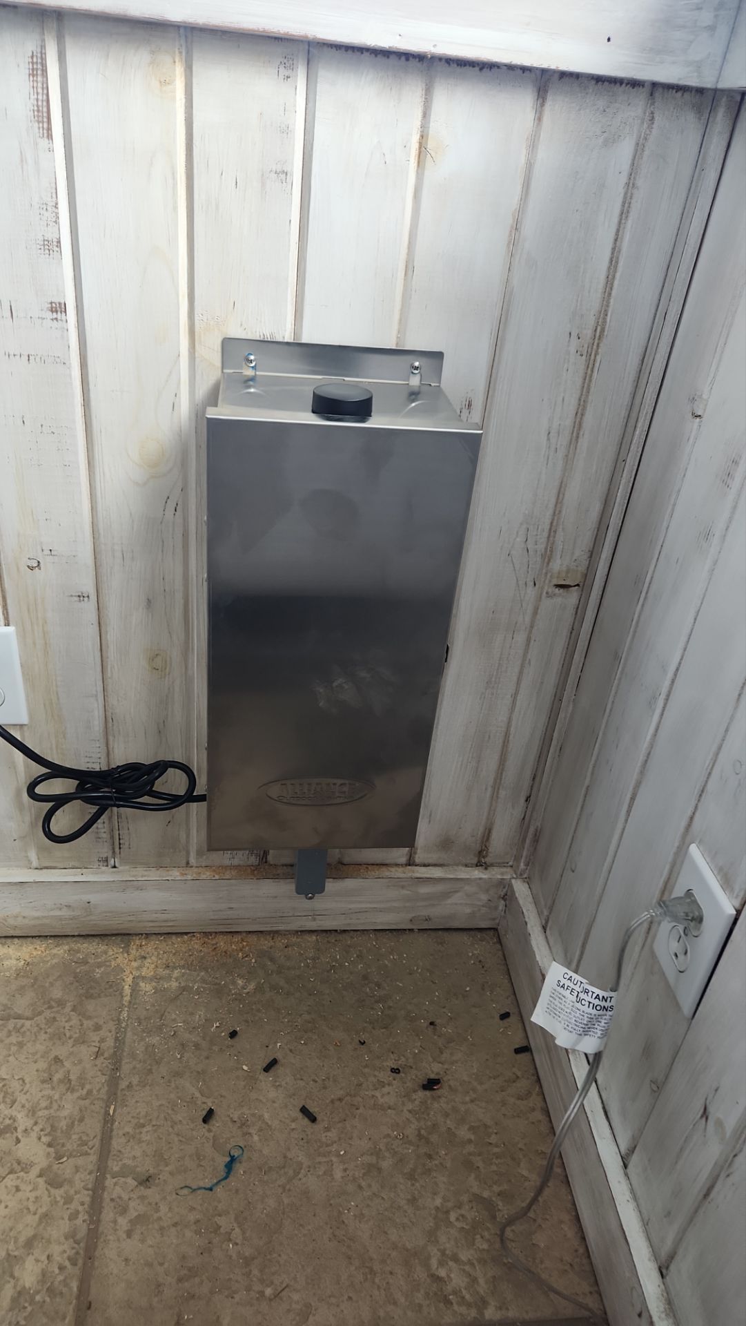 A stainless steel box is hanging on a wall in a room.