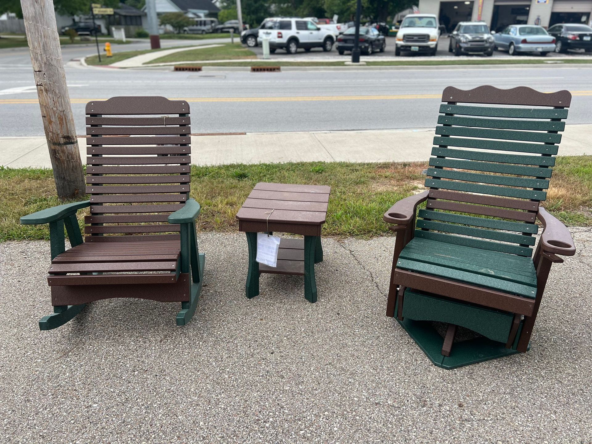 Two rocking chairs and a table are sitting on the side of the road.