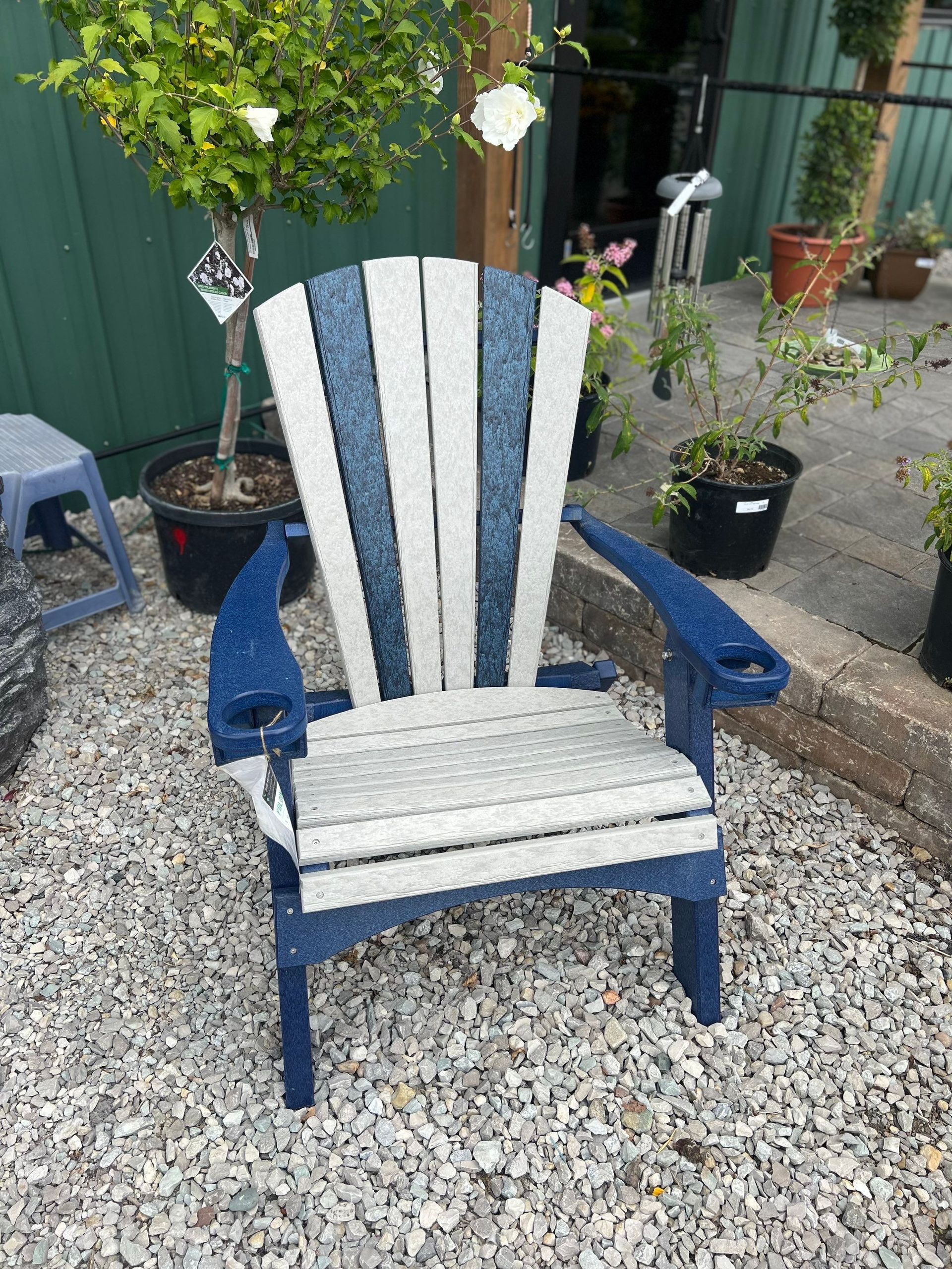 A blue and white adirondack chair is sitting on a pile of gravel.