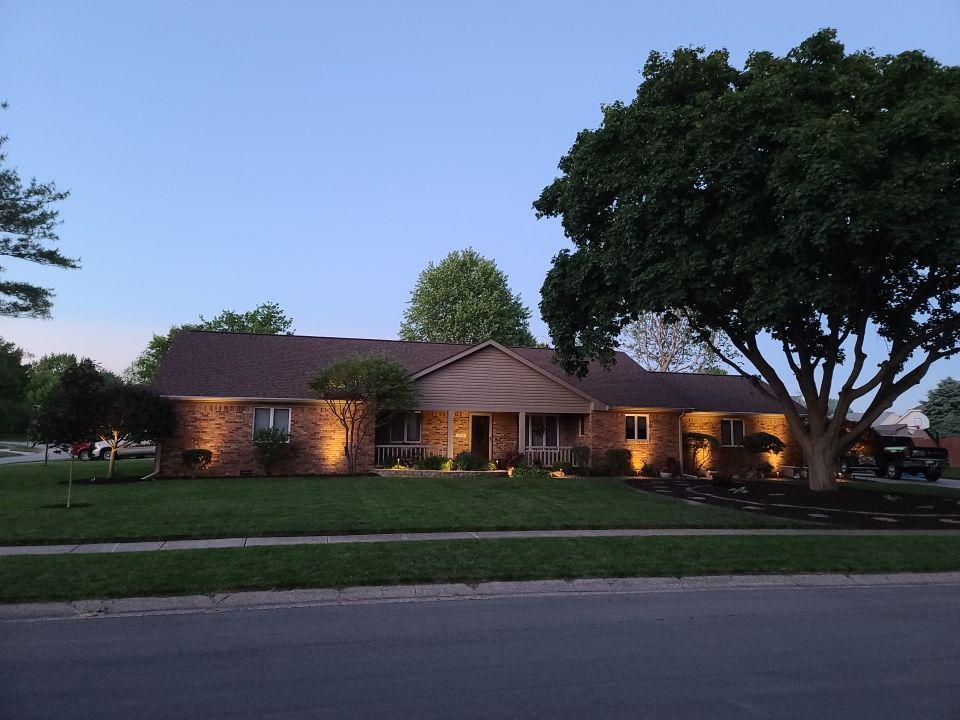 A house with a tree in front of it is lit up at night
