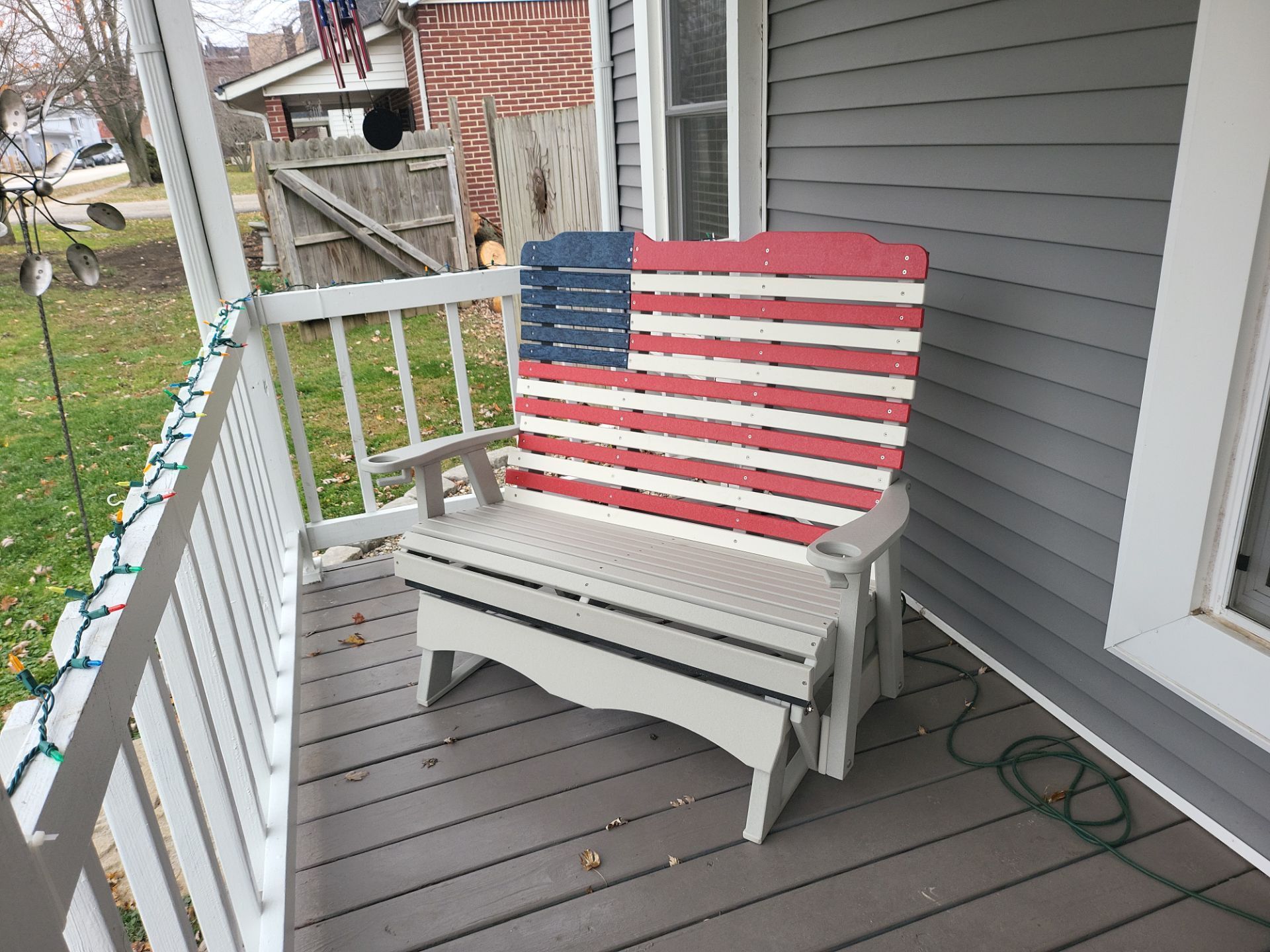 A red , white and blue american flag bench is on a porch.