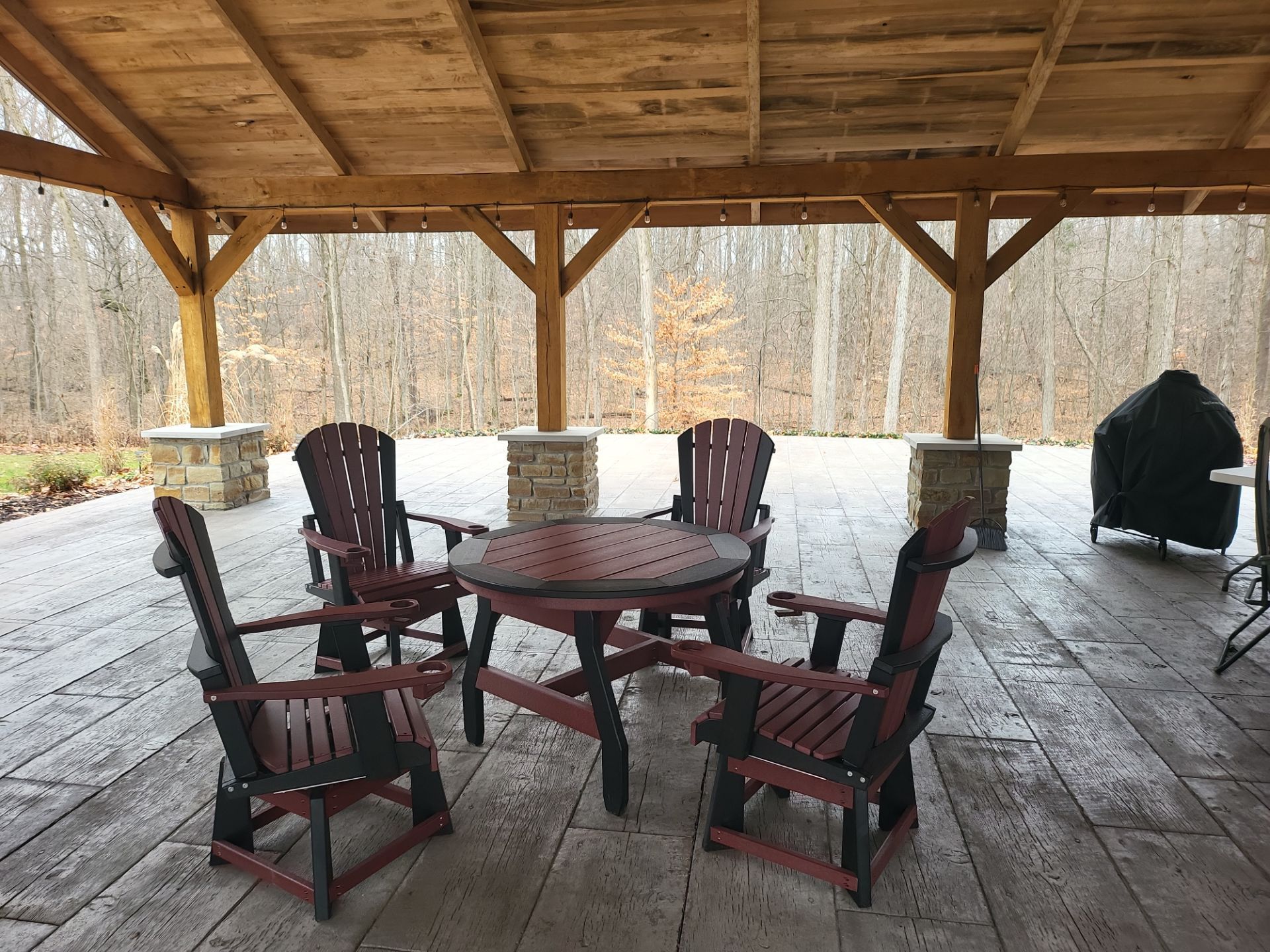 A patio with a table and chairs under a wooden roof