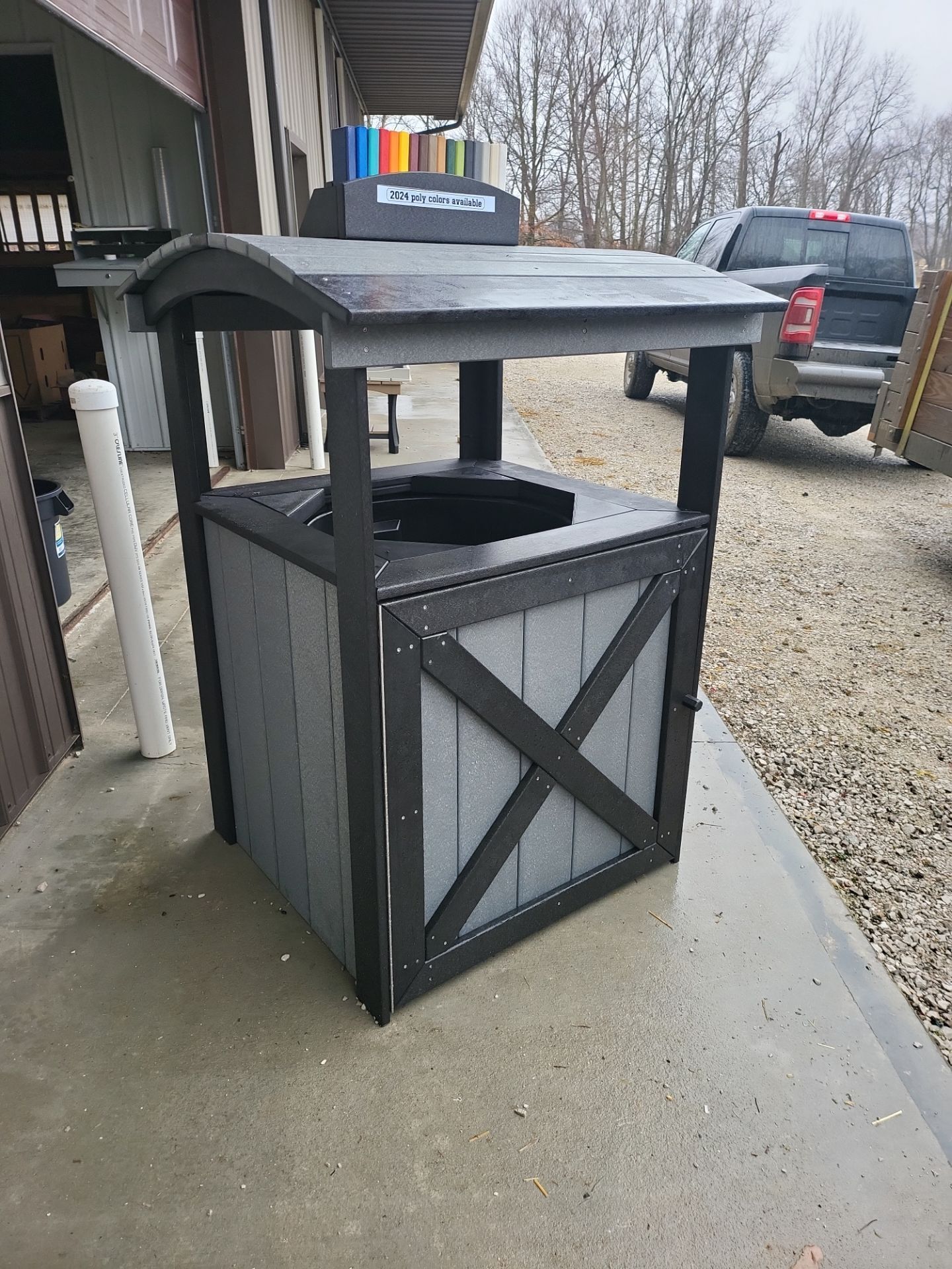 A trash can is sitting on a sidewalk next to a building.
