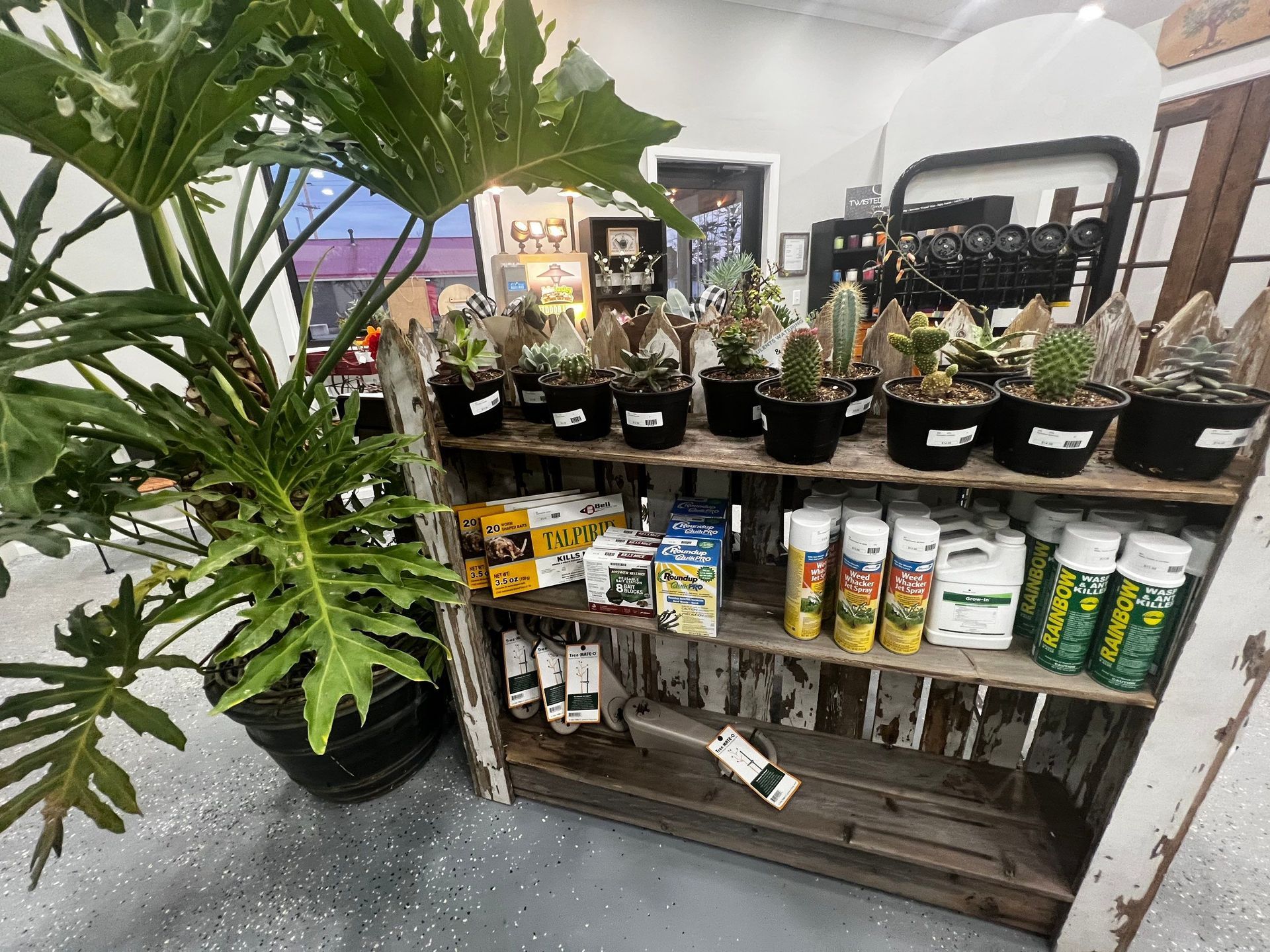 A shelf filled with potted plants and bottles of fertilizer.