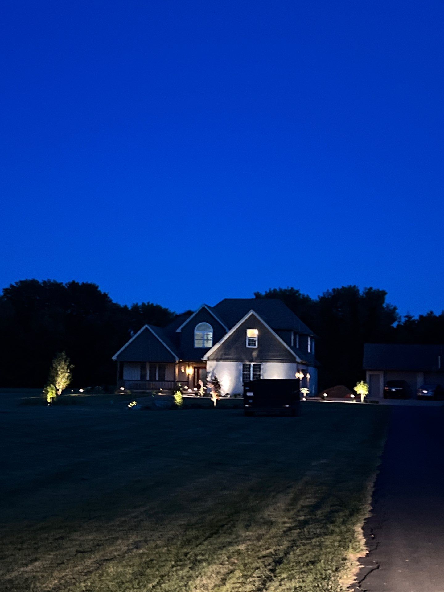A house is lit up at night with a blue sky in the background