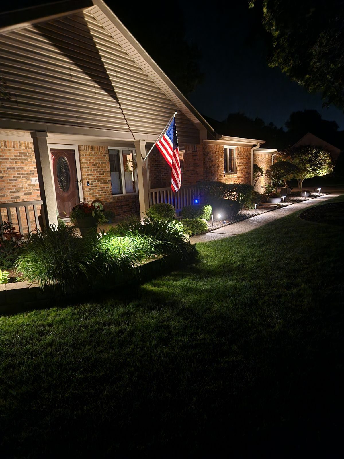 A house with an american flag on the front porch at night.