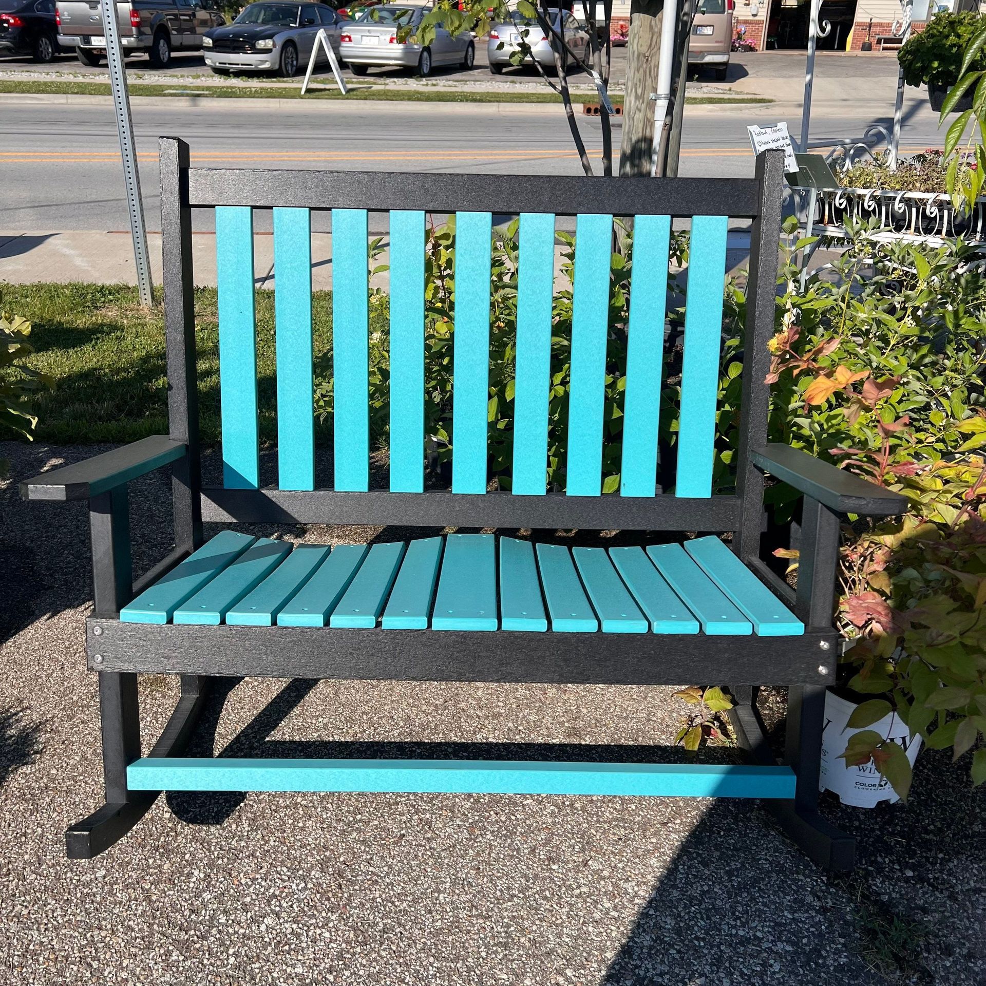 A black and blue rocking bench is sitting on the sidewalk.