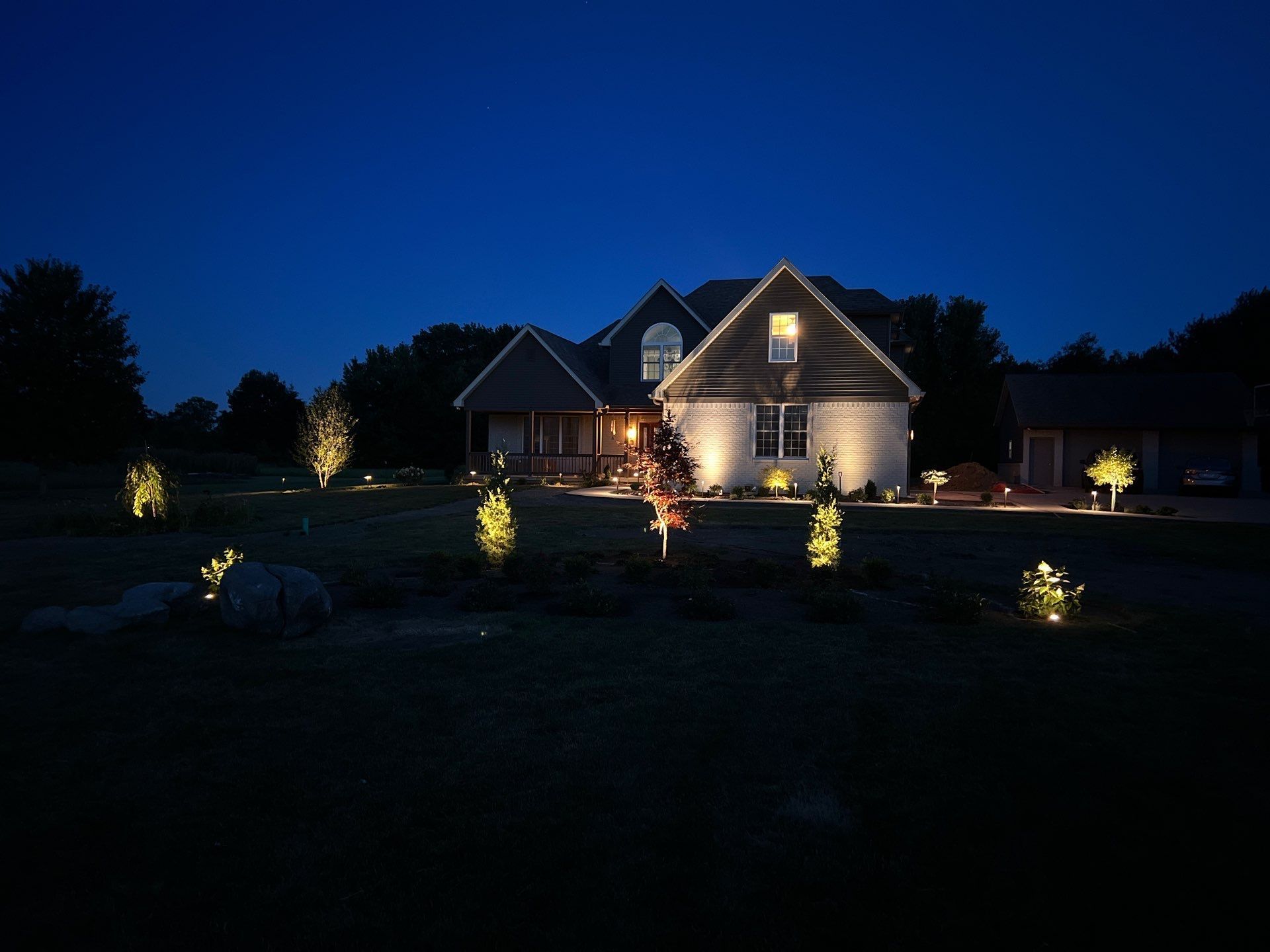 A house is lit up at night with trees in front of it