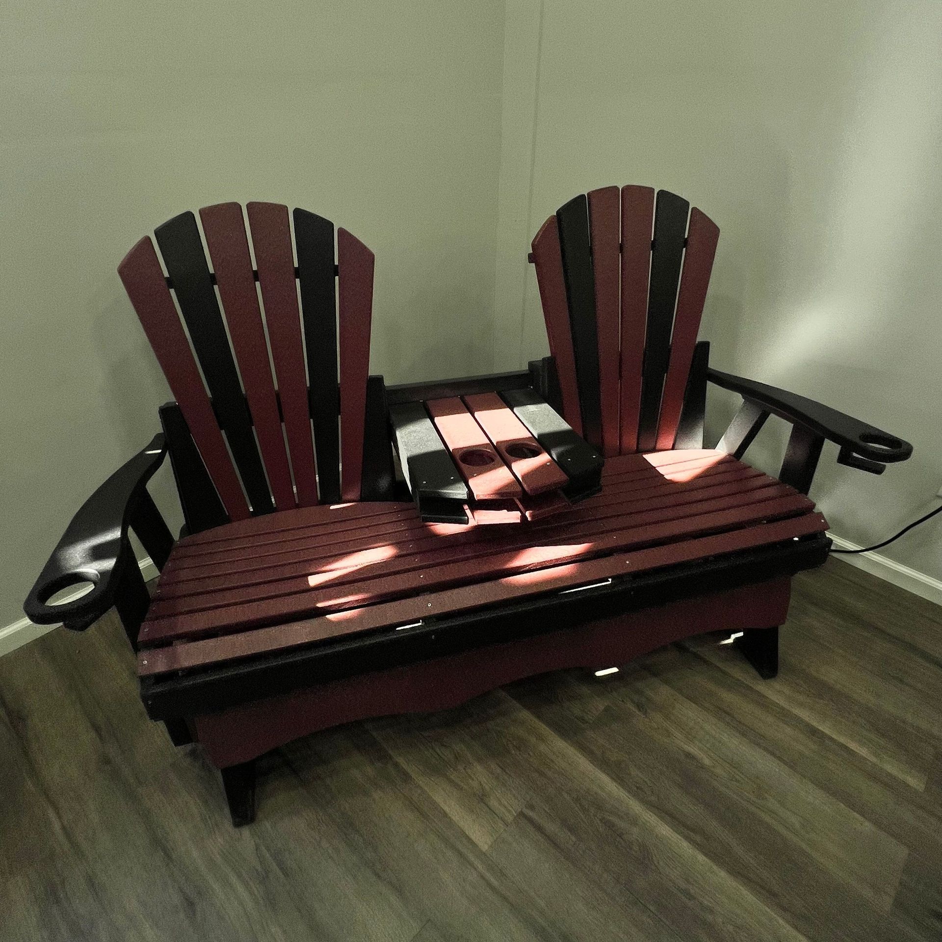 A wooden bench with two red and black chairs on it