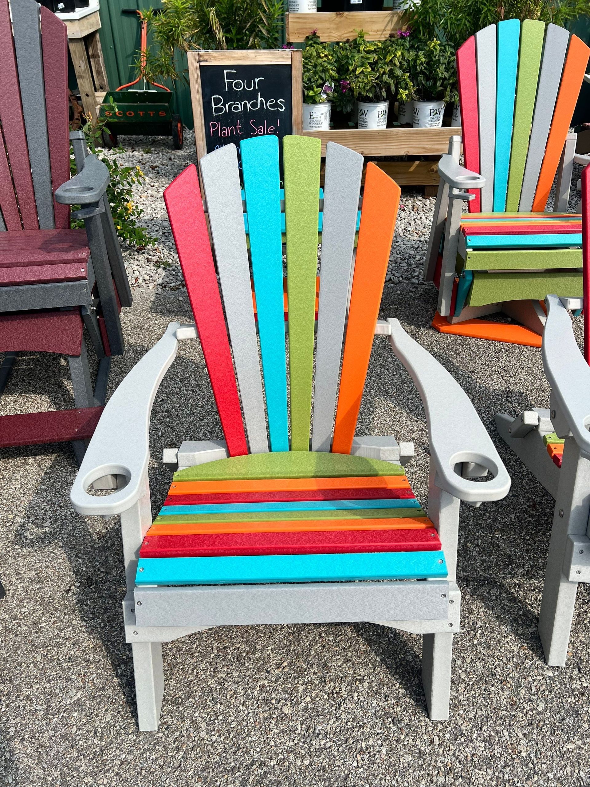 A row of colorful adirondack chairs are sitting on gravel.