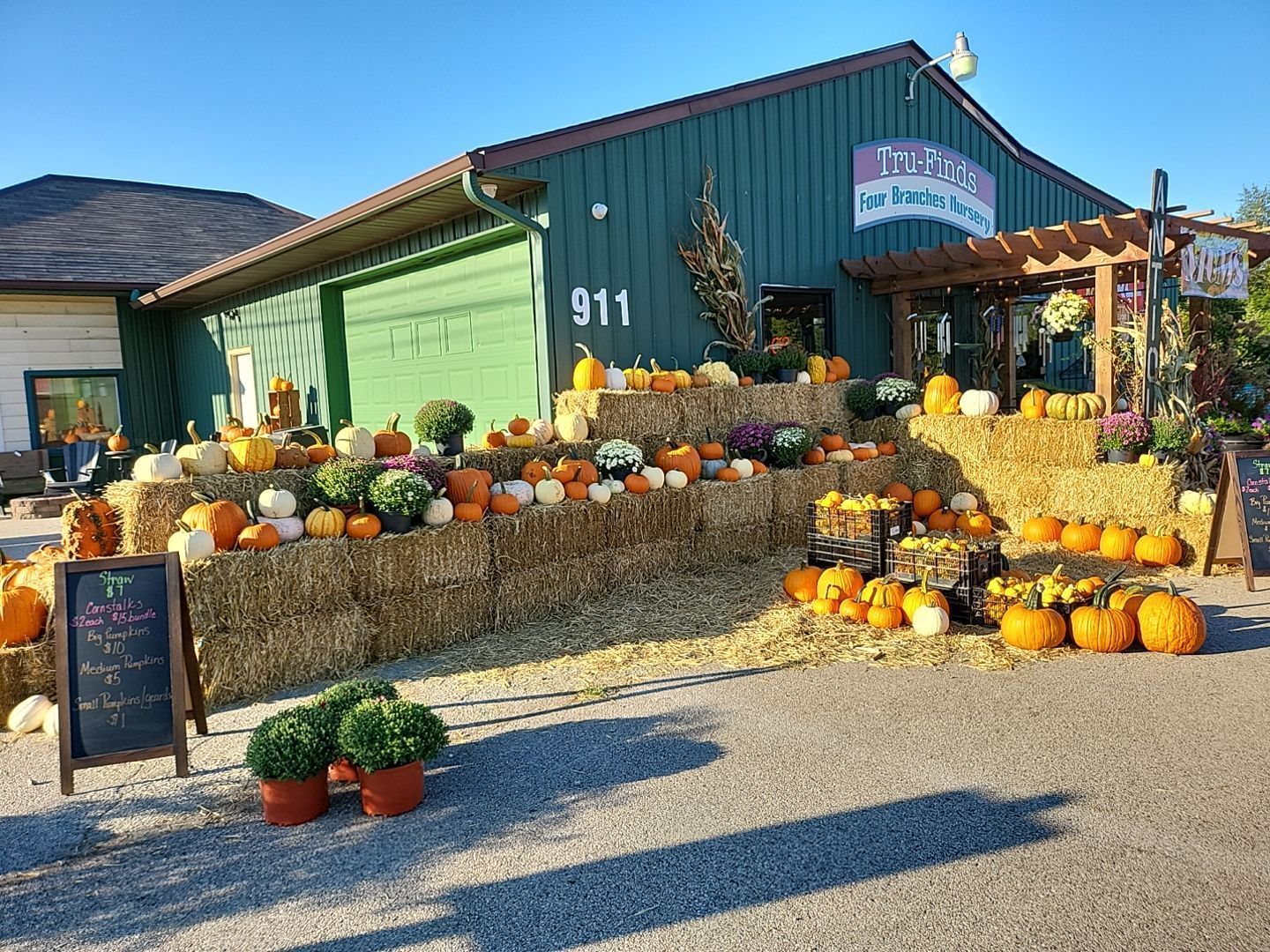 A pumpkin patch with pumpkins and hay bales in front of a building.