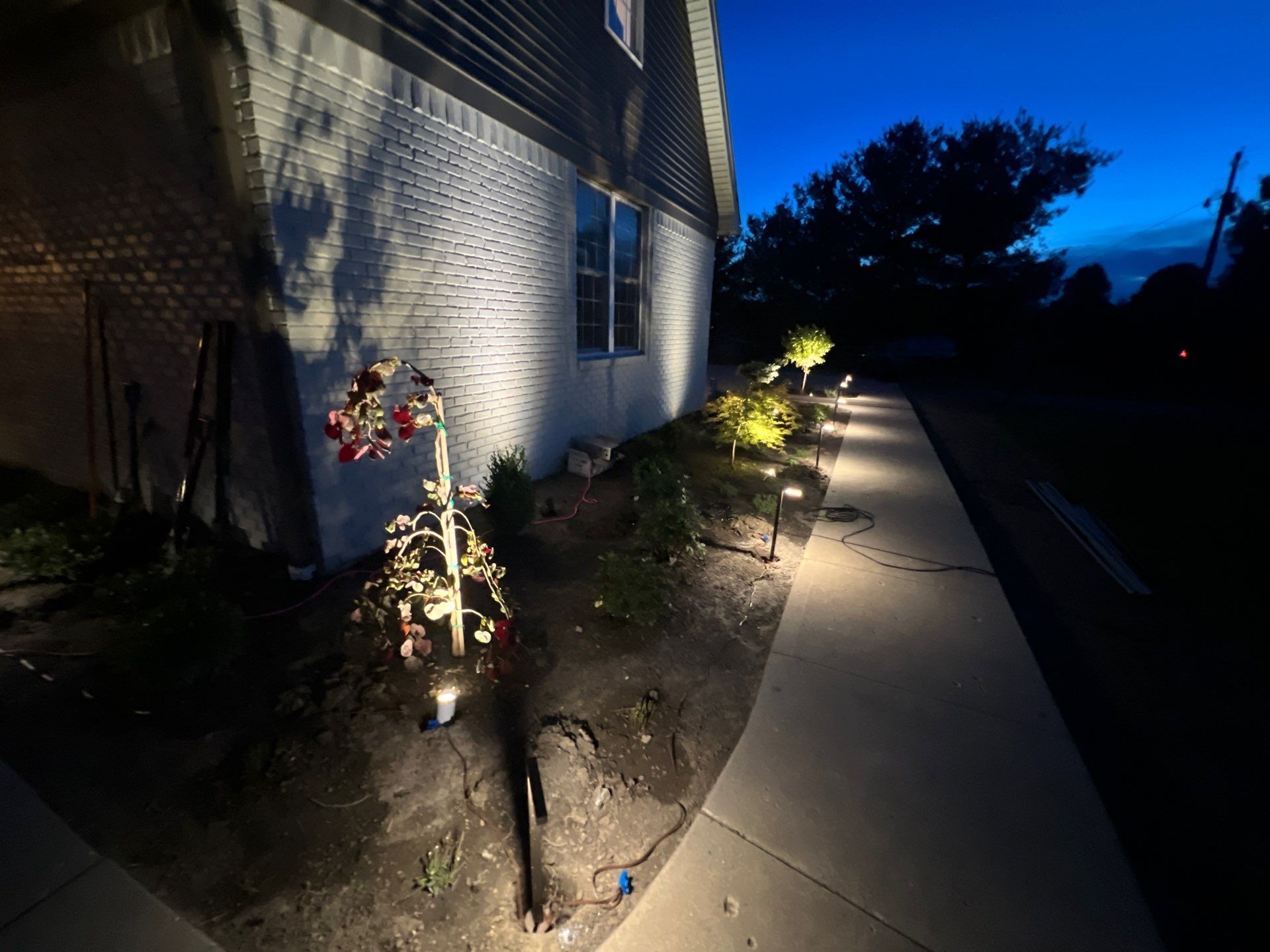 A sidewalk is lit up at night in front of a house.