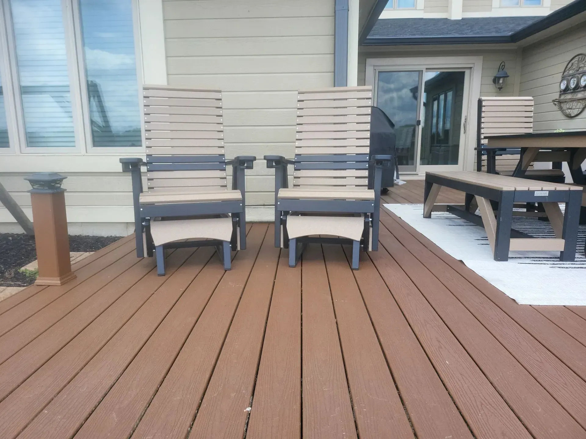 A wooden deck with chairs and ottomans on it