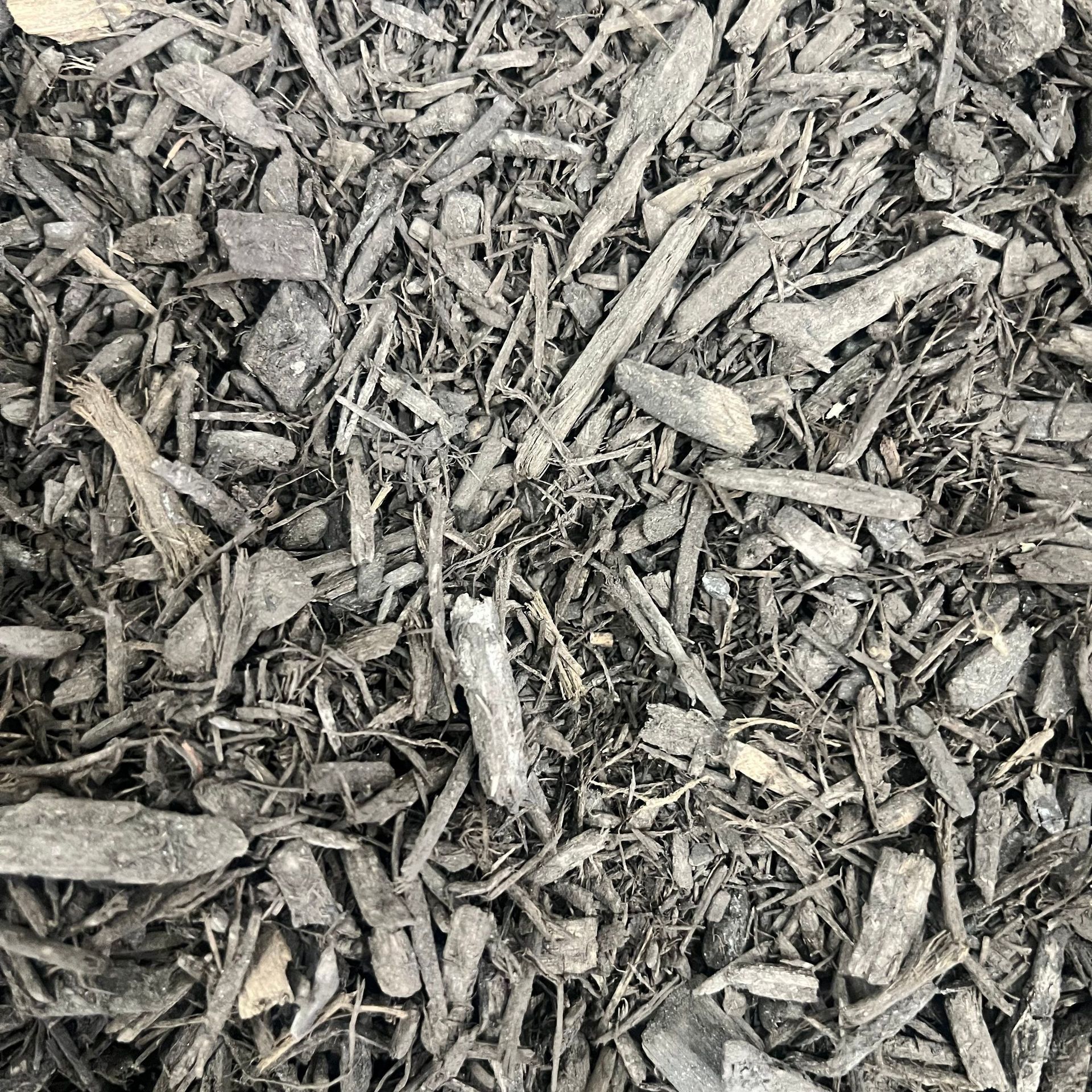 A pile of black mulch is sitting on the ground.