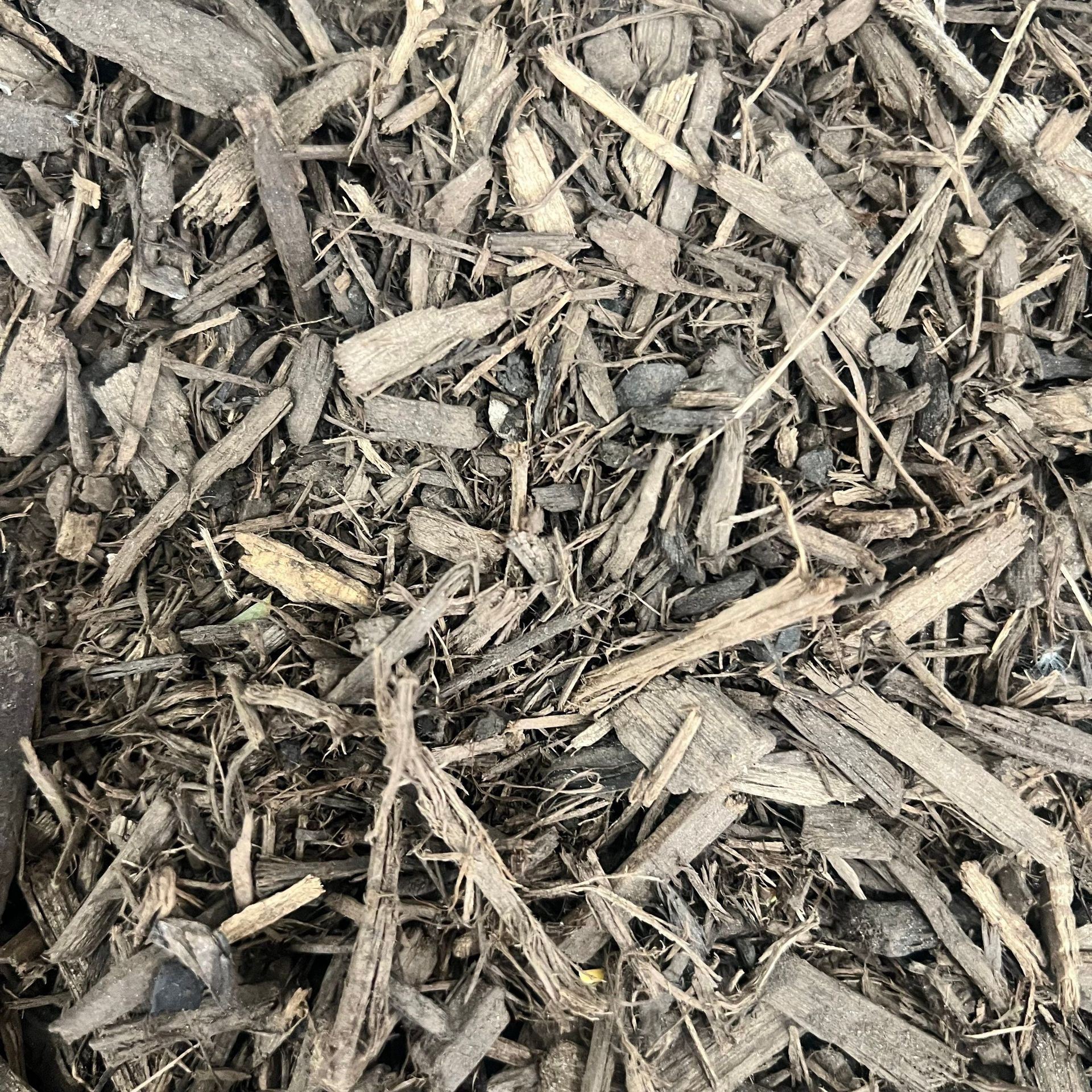 A pile of brown mulch is sitting on the ground.
