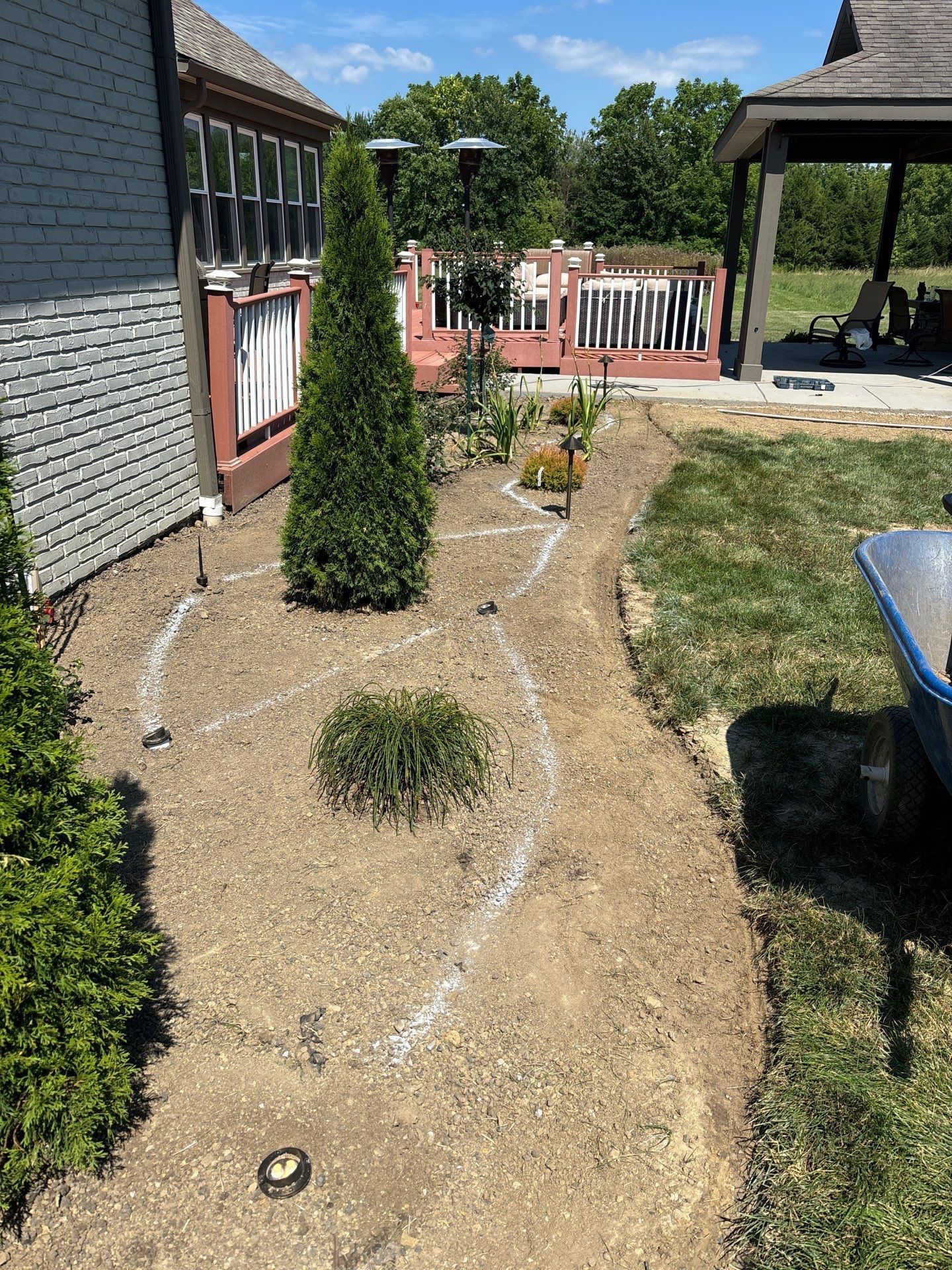 A wheelbarrow is sitting in the dirt in front of a house.
