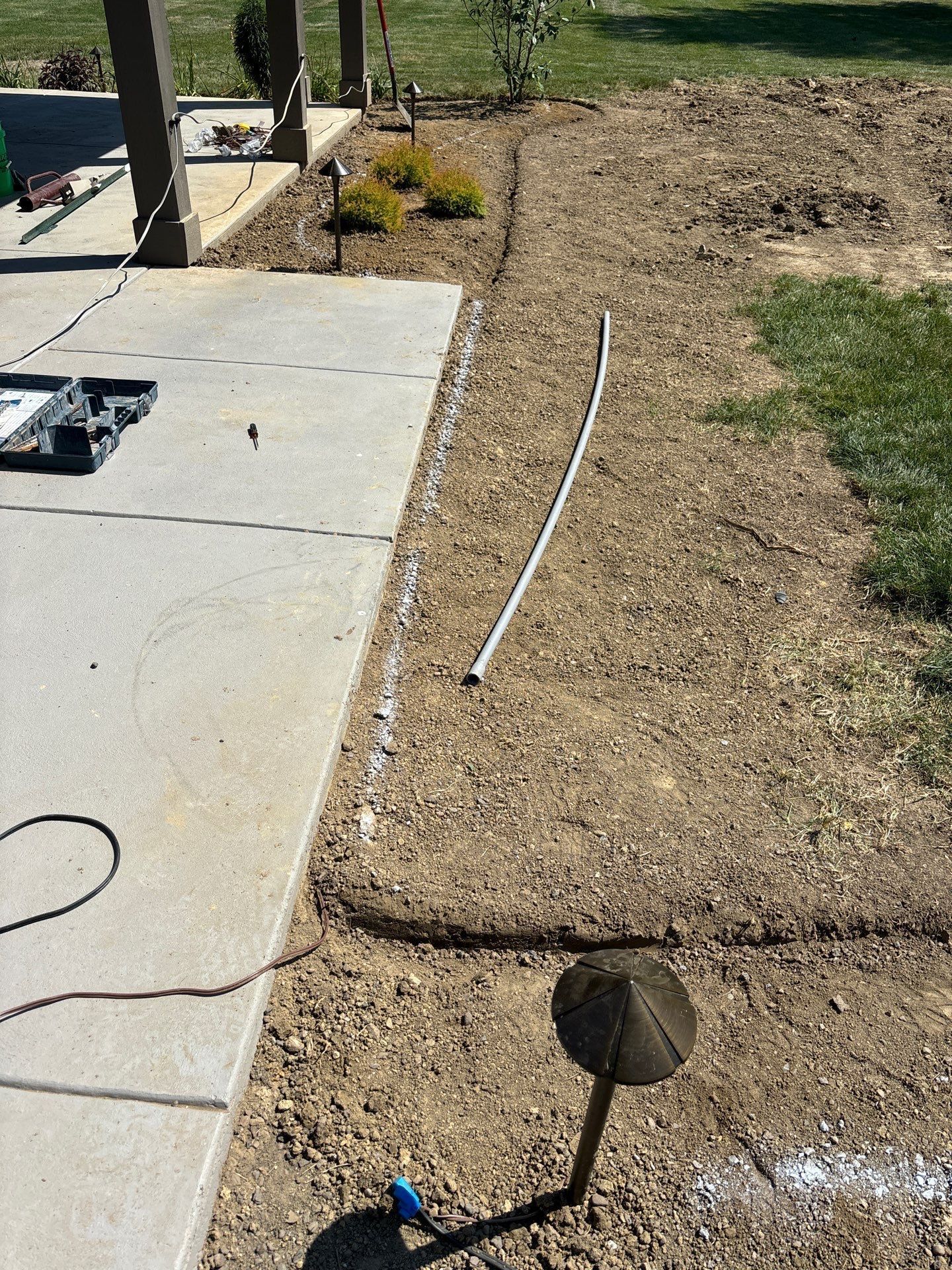 A shovel is sitting in the dirt next to a concrete walkway.