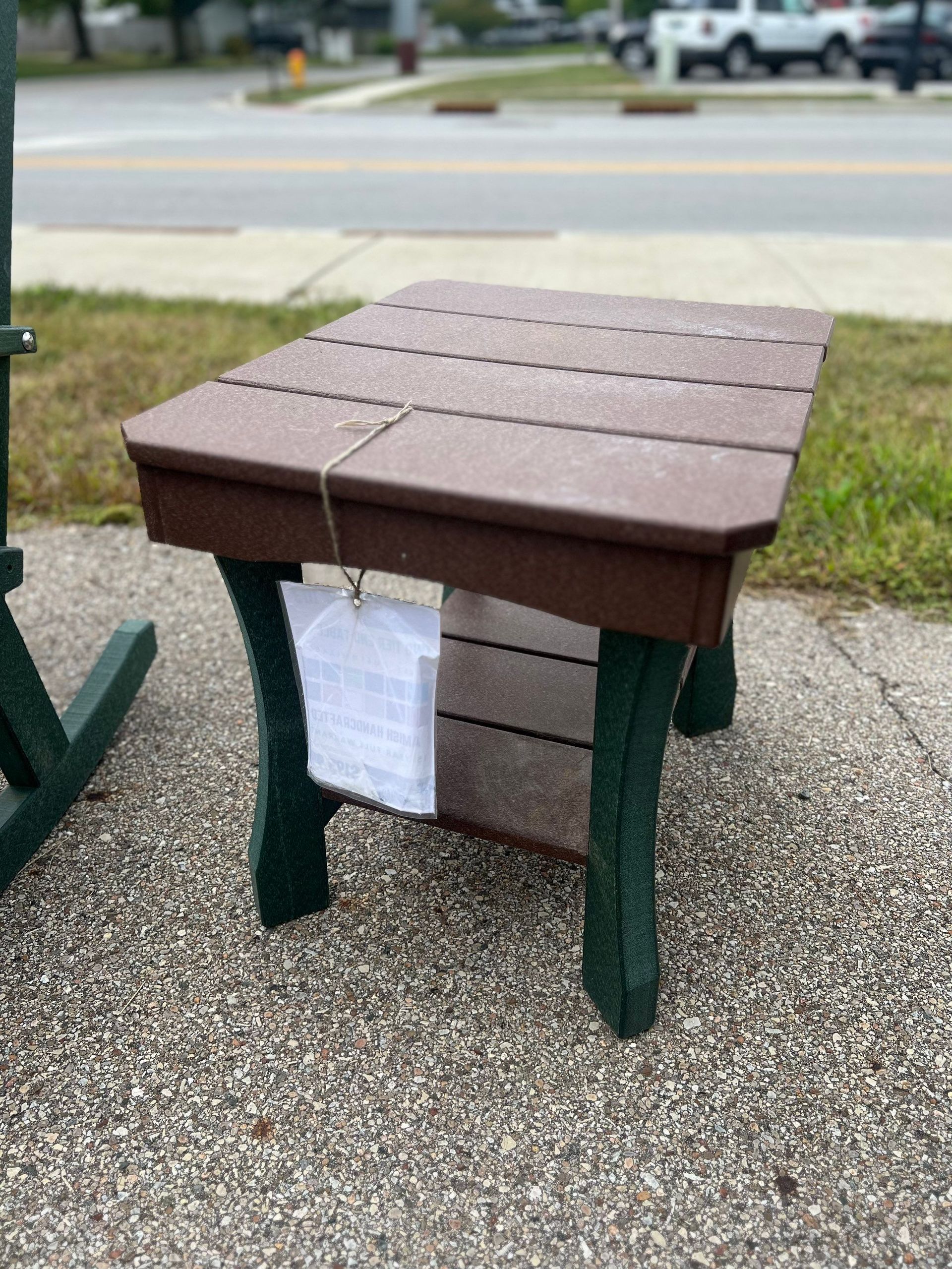 A small table with a tag on it is sitting on the sidewalk.