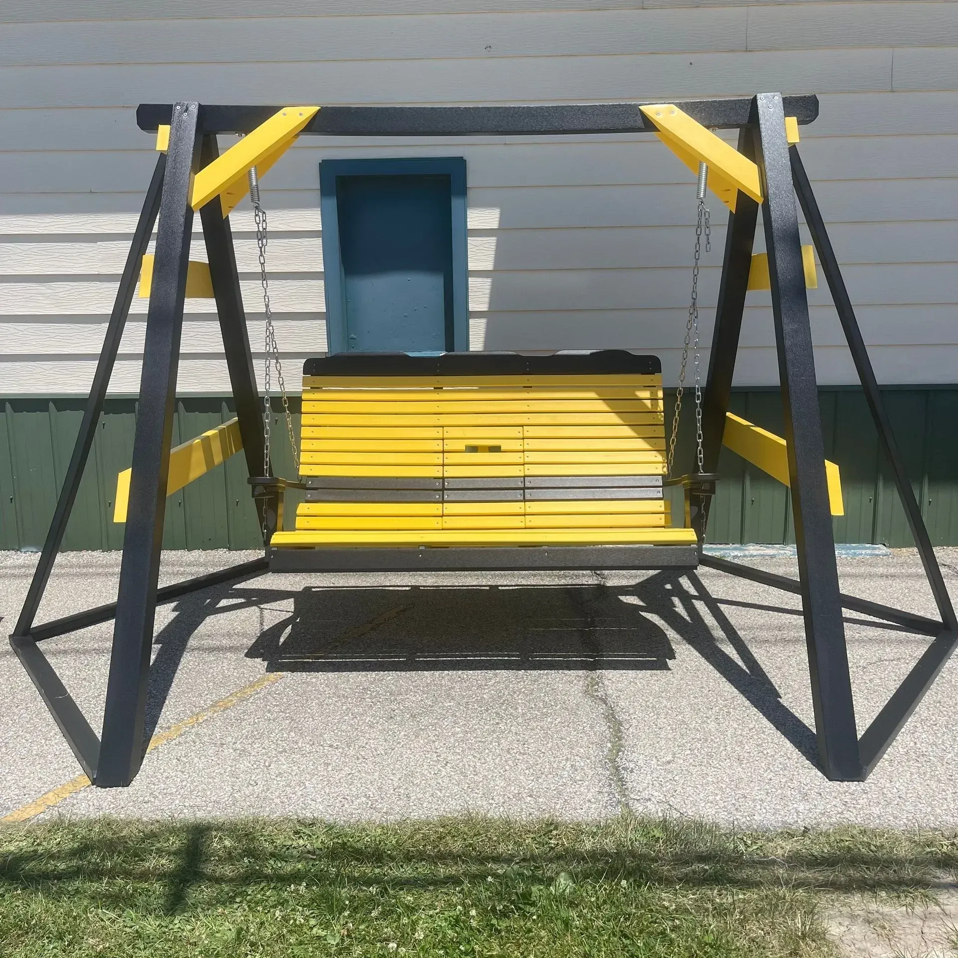 A yellow and black swing is sitting in front of a house