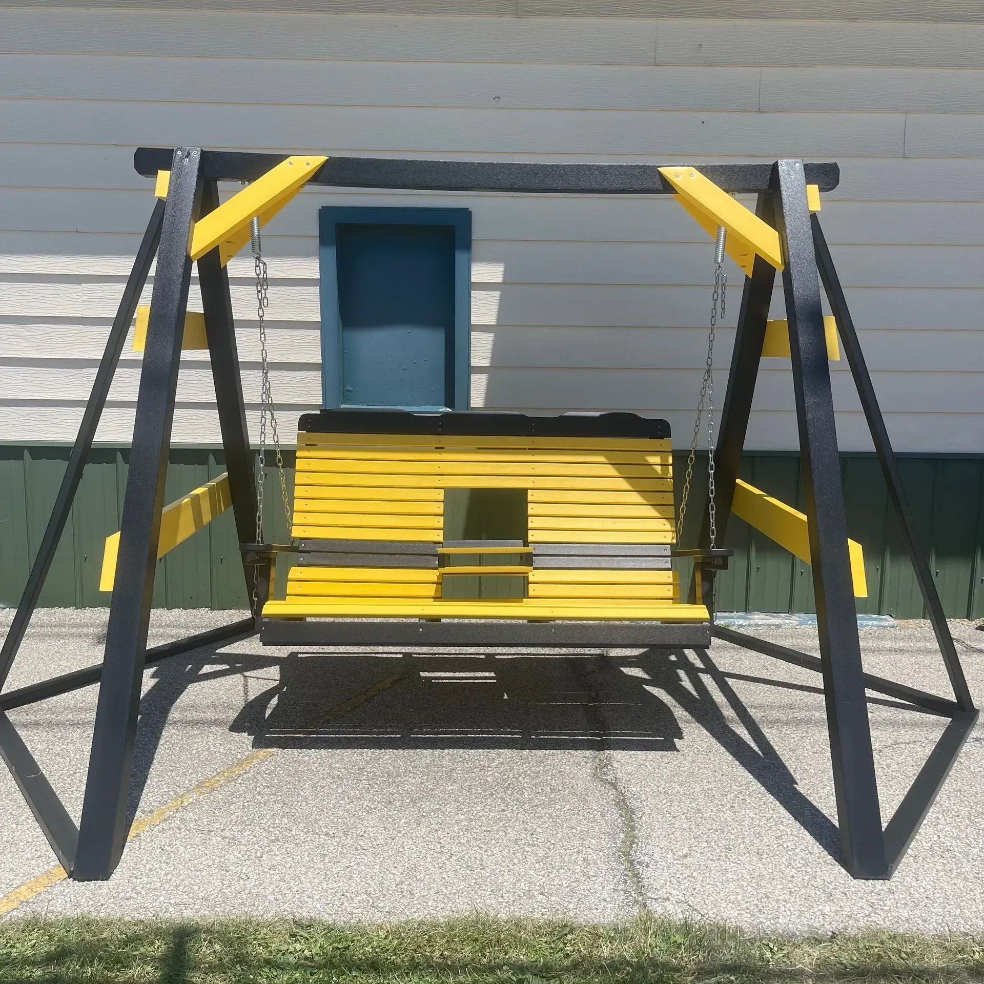 A yellow and black swing is sitting in front of a house