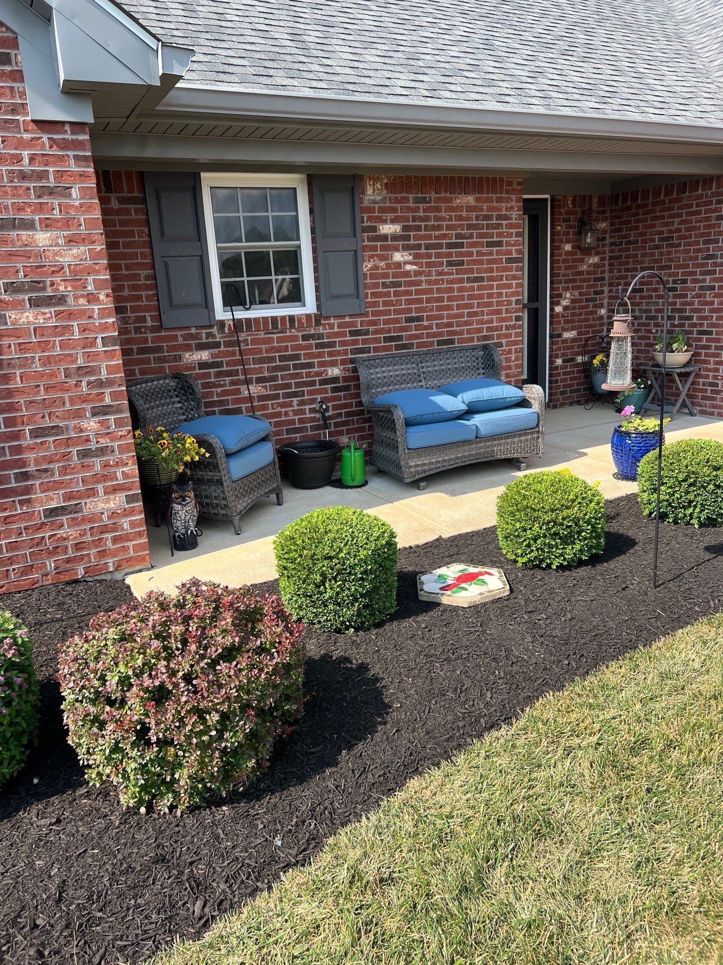 A brick house with a patio with a blue couch and chairs.