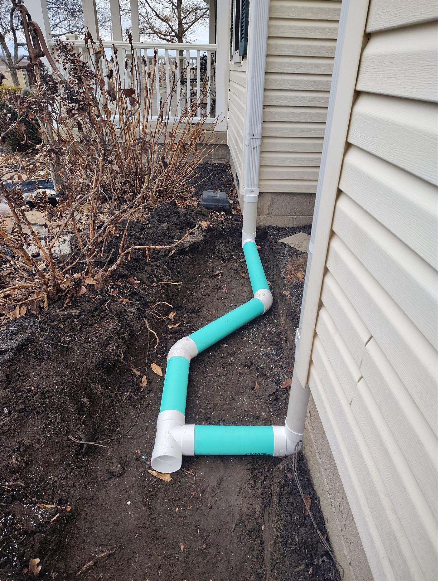 A drain pipe is being installed on the side of a house.