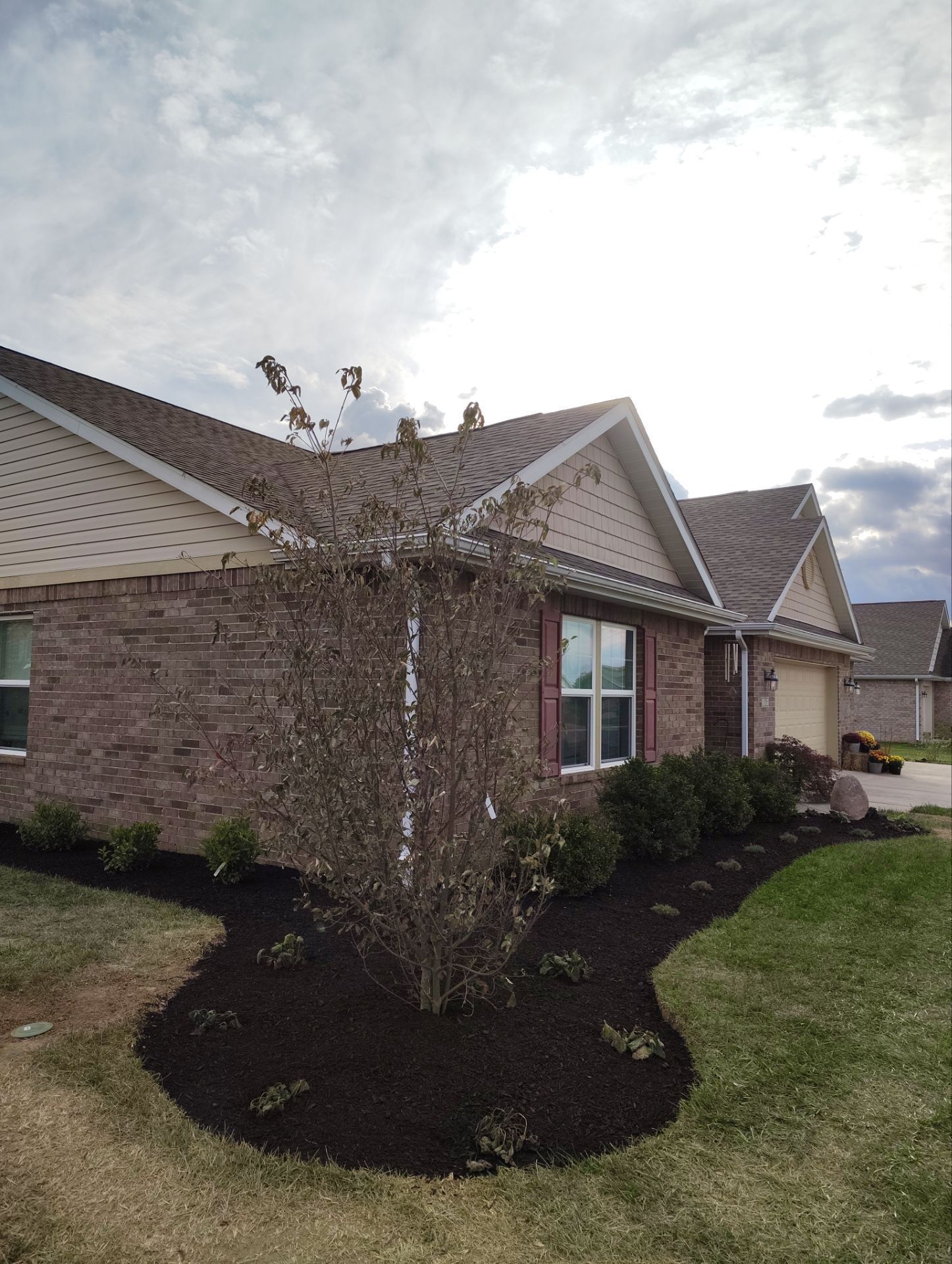 A brick house with a tree in front of it.
