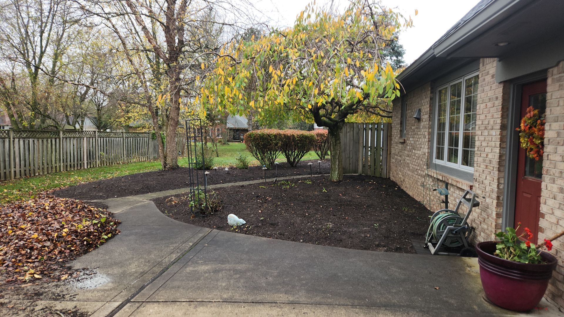 A brick house with a red door and a tree in front of it.