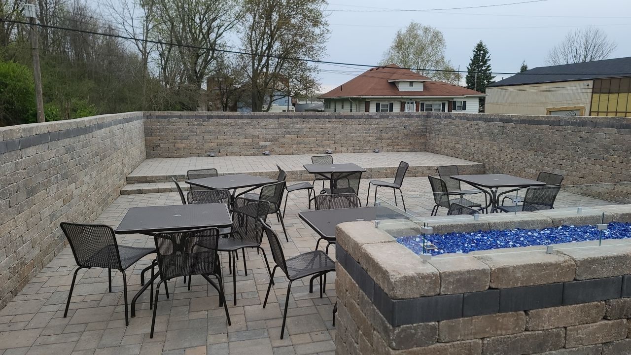 A patio with tables and chairs and a fire pit.