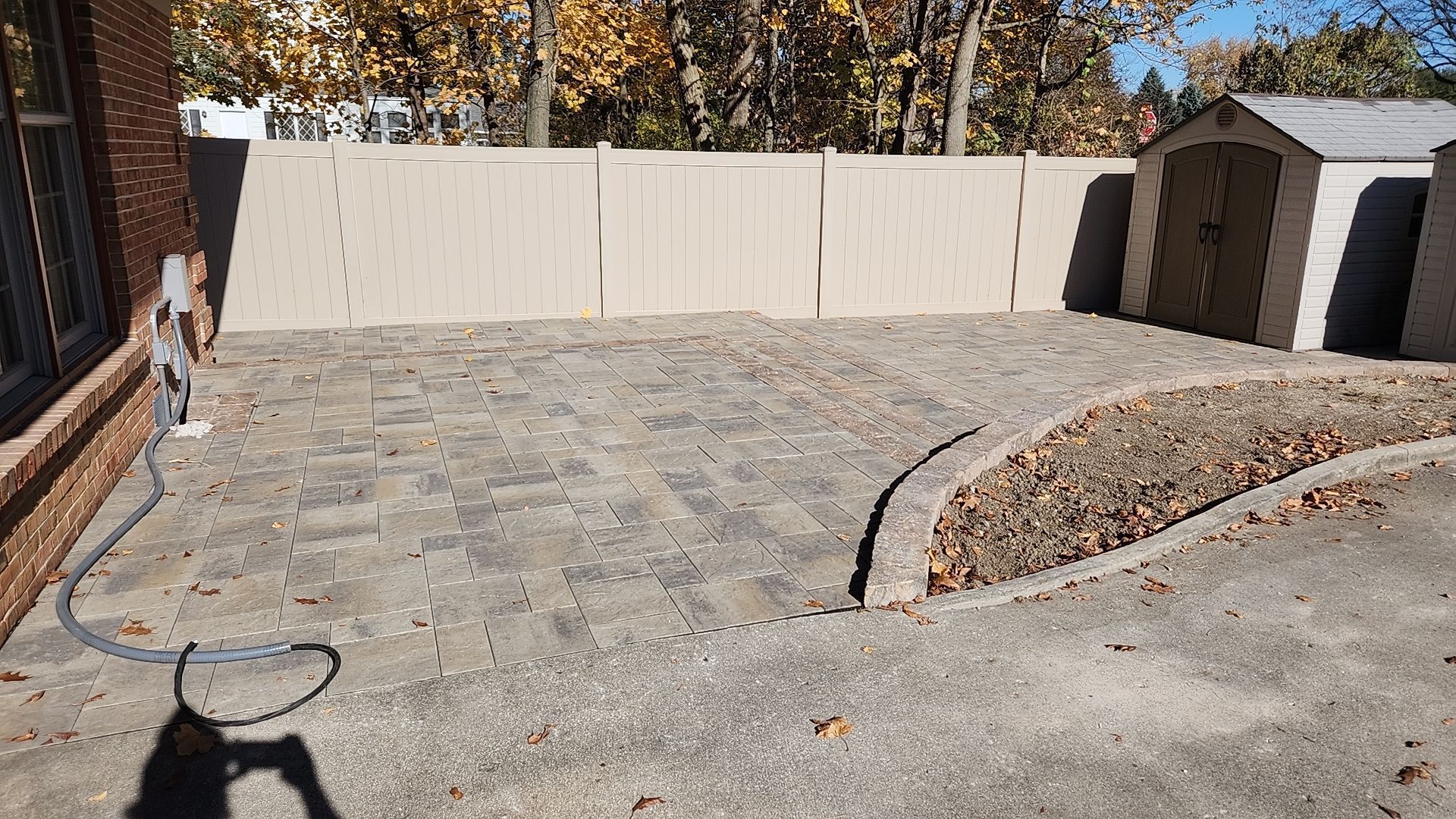 There is a shadow of a person on the ground in the backyard.