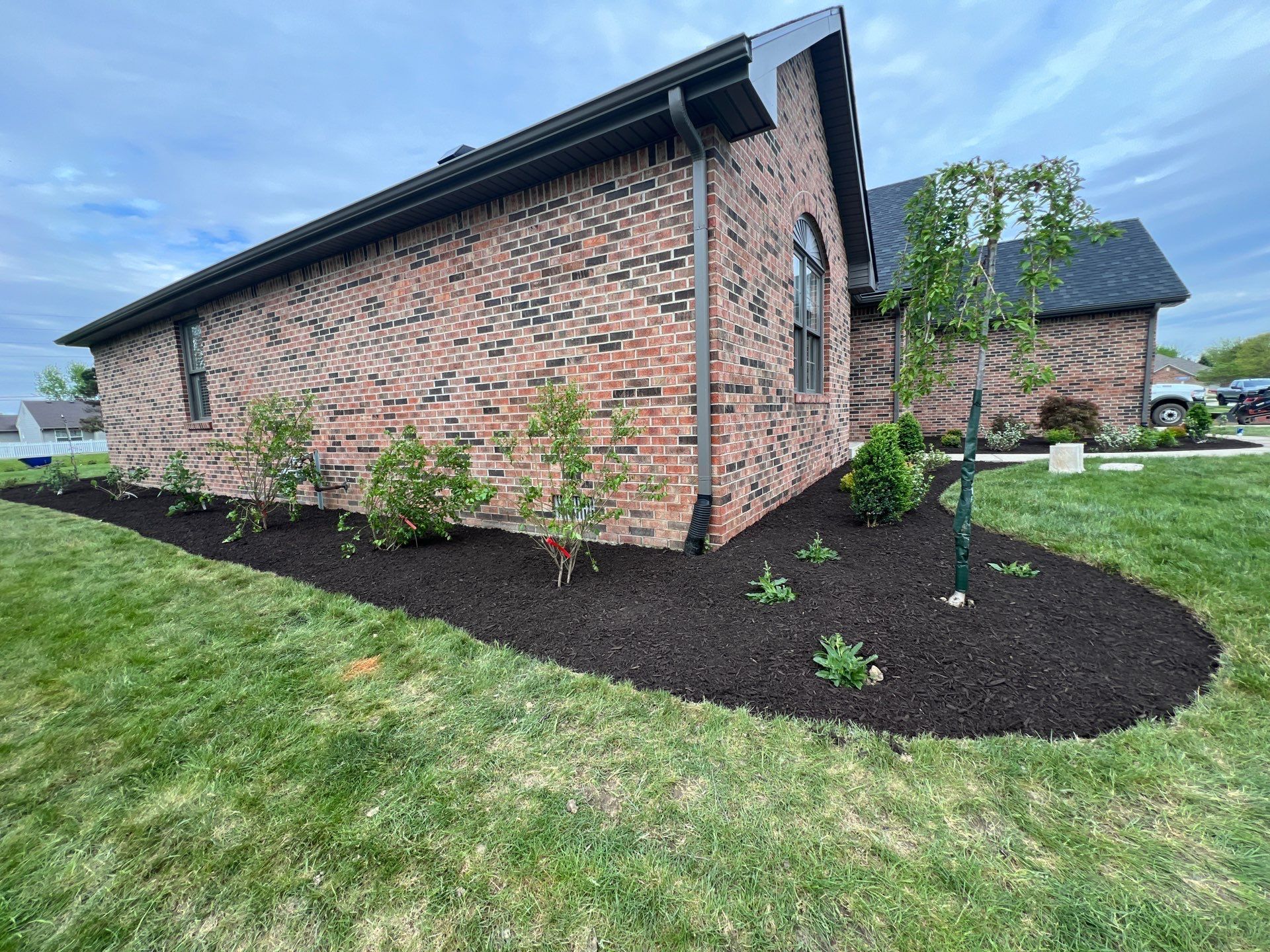 A brick house with a lush green lawn in front of it.