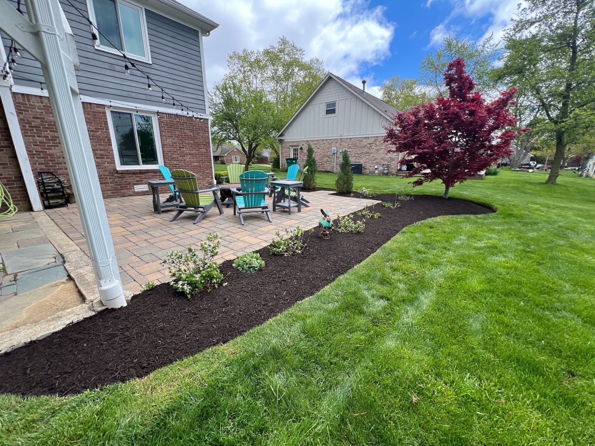 A backyard with a patio and chairs in front of a house.