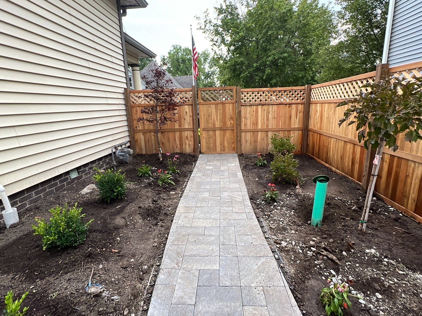 A walkway leading to a wooden gate in a backyard.