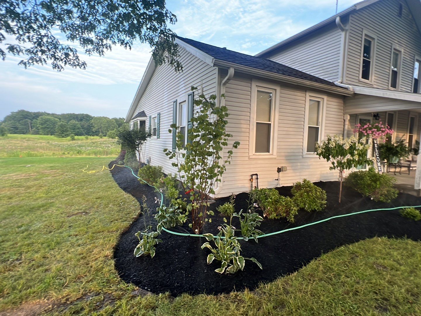 A white house with a black mulch bed in front of it.