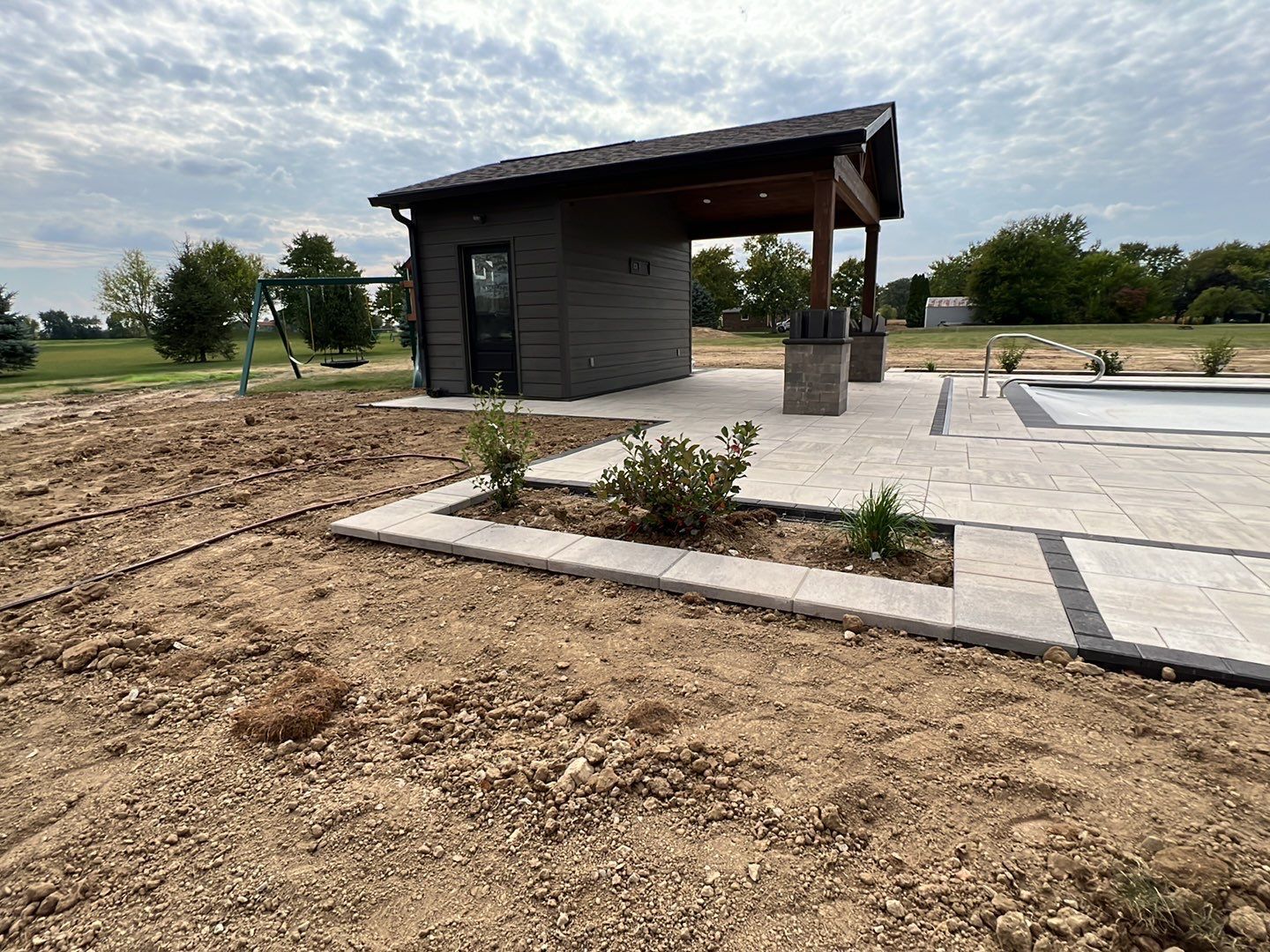 A small house is sitting next to a swimming pool.