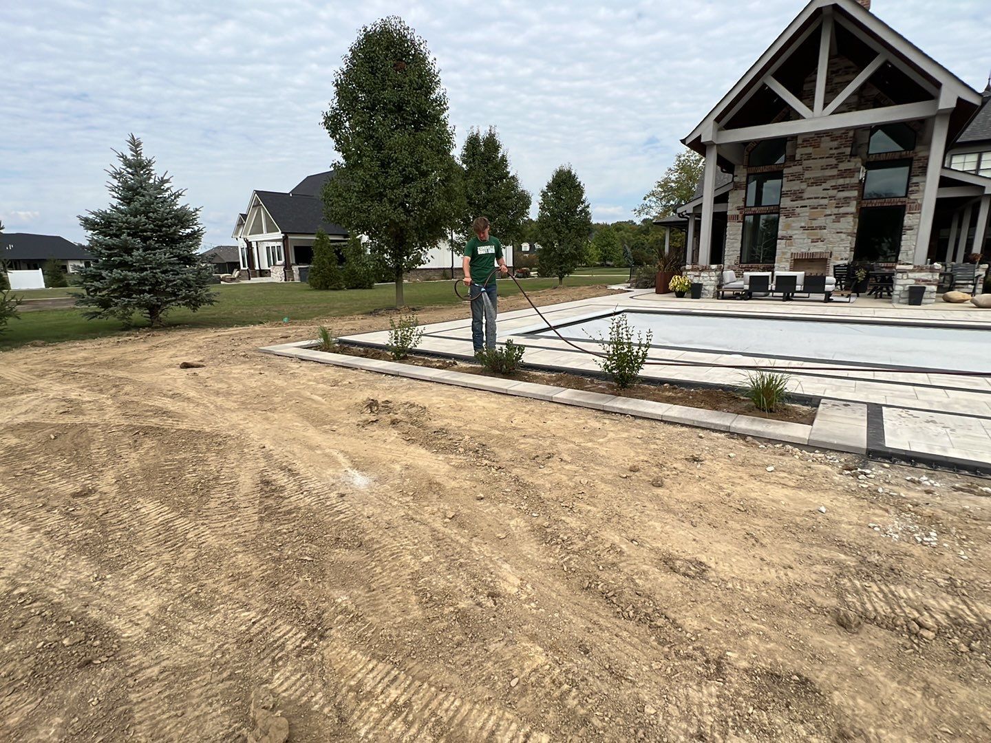 A man is standing in front of a house next to a pool.