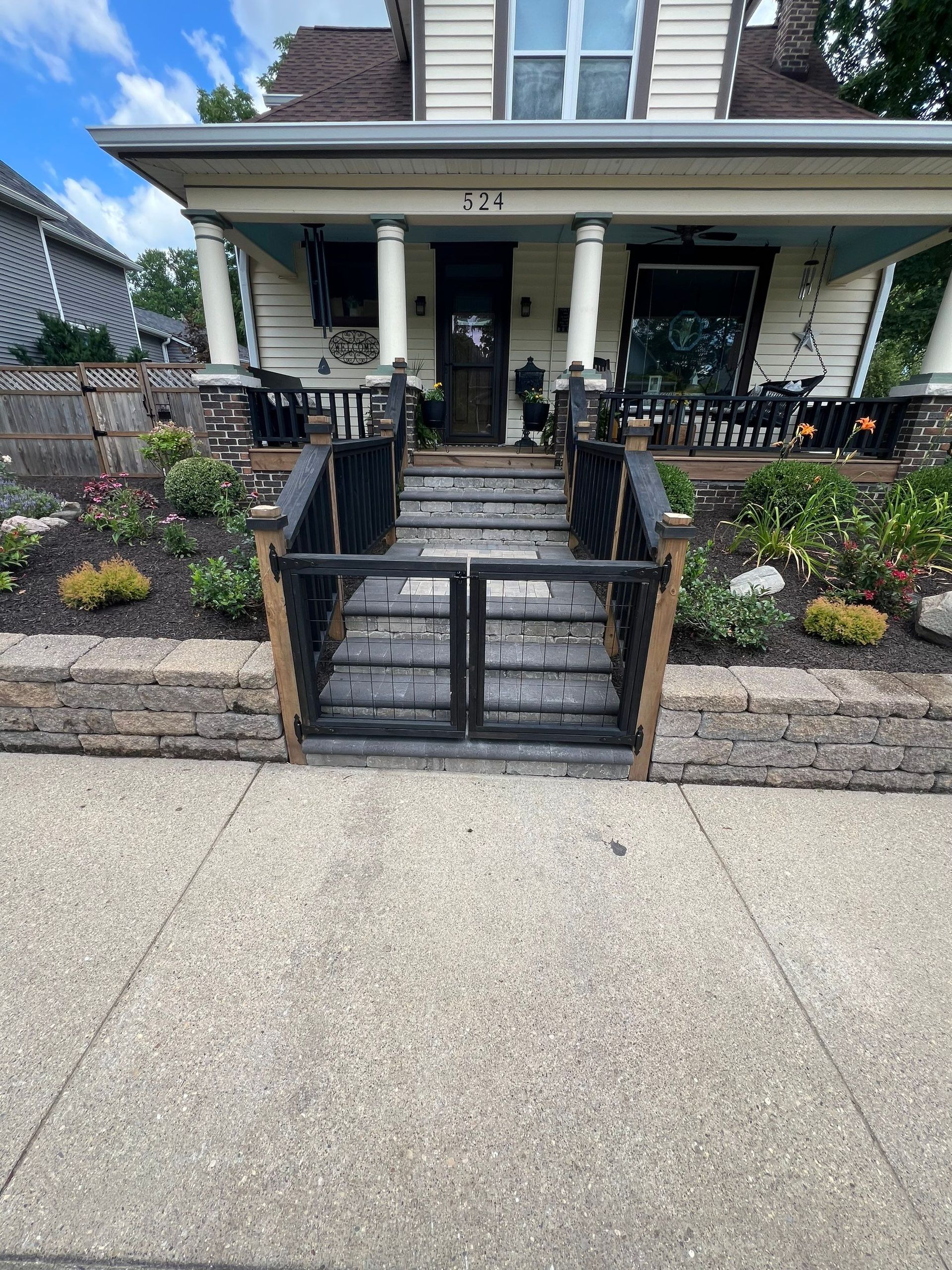 The front of a house with a fence and stairs leading up to it.