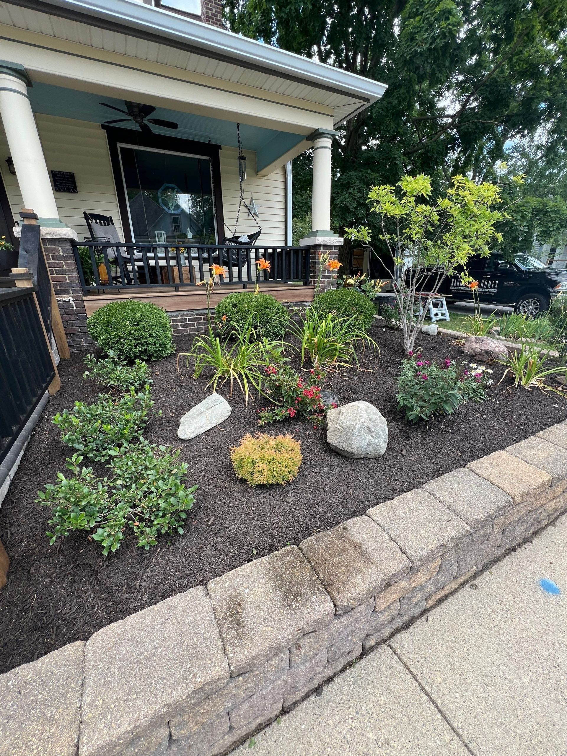 A house with a porch and a garden in front of it.