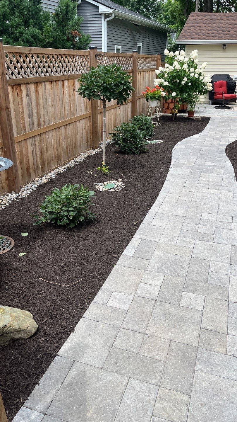 A patio with a wooden fence and a walkway leading to a house.