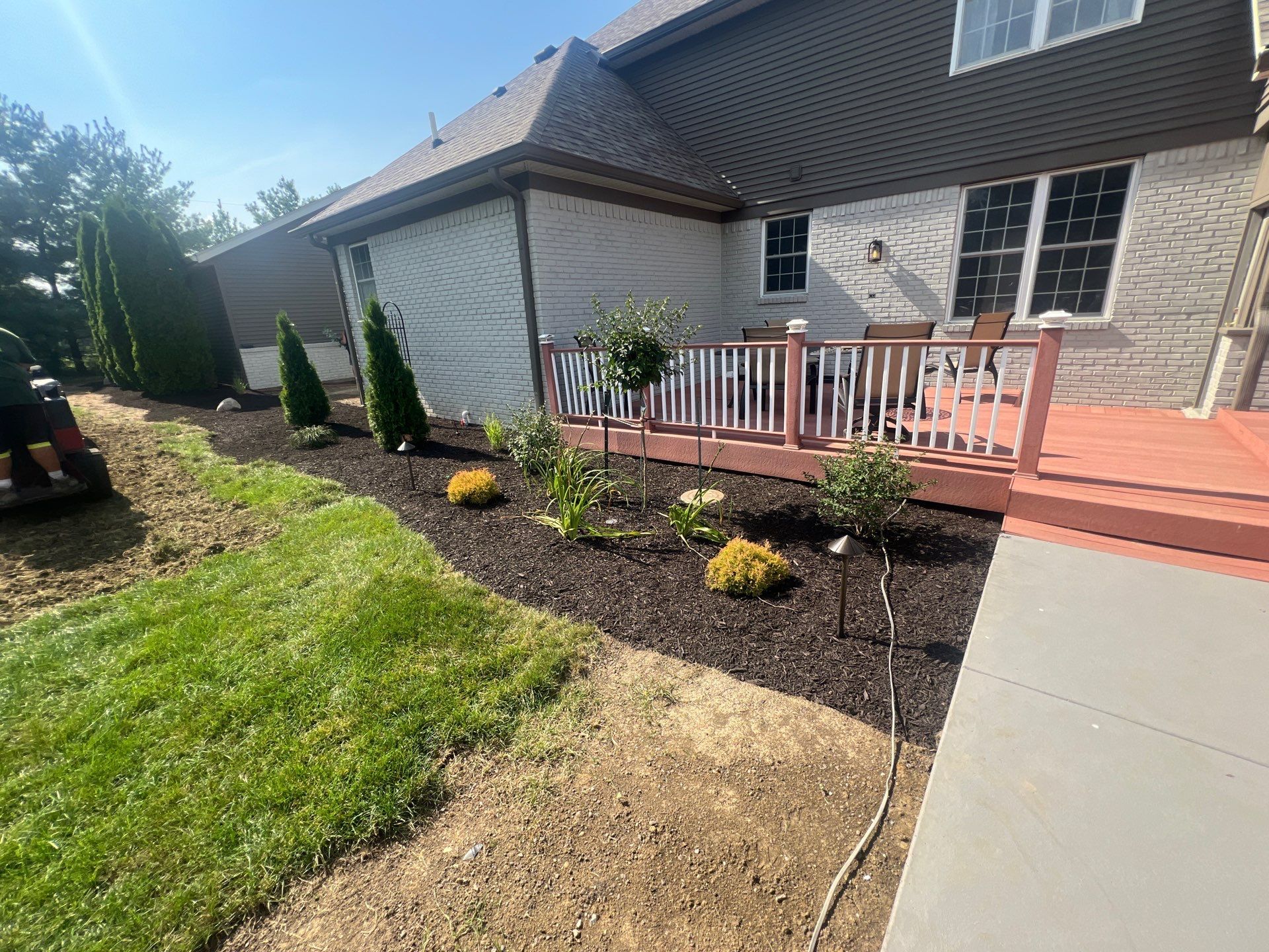 A house with a deck and a lawn mower in front of it.