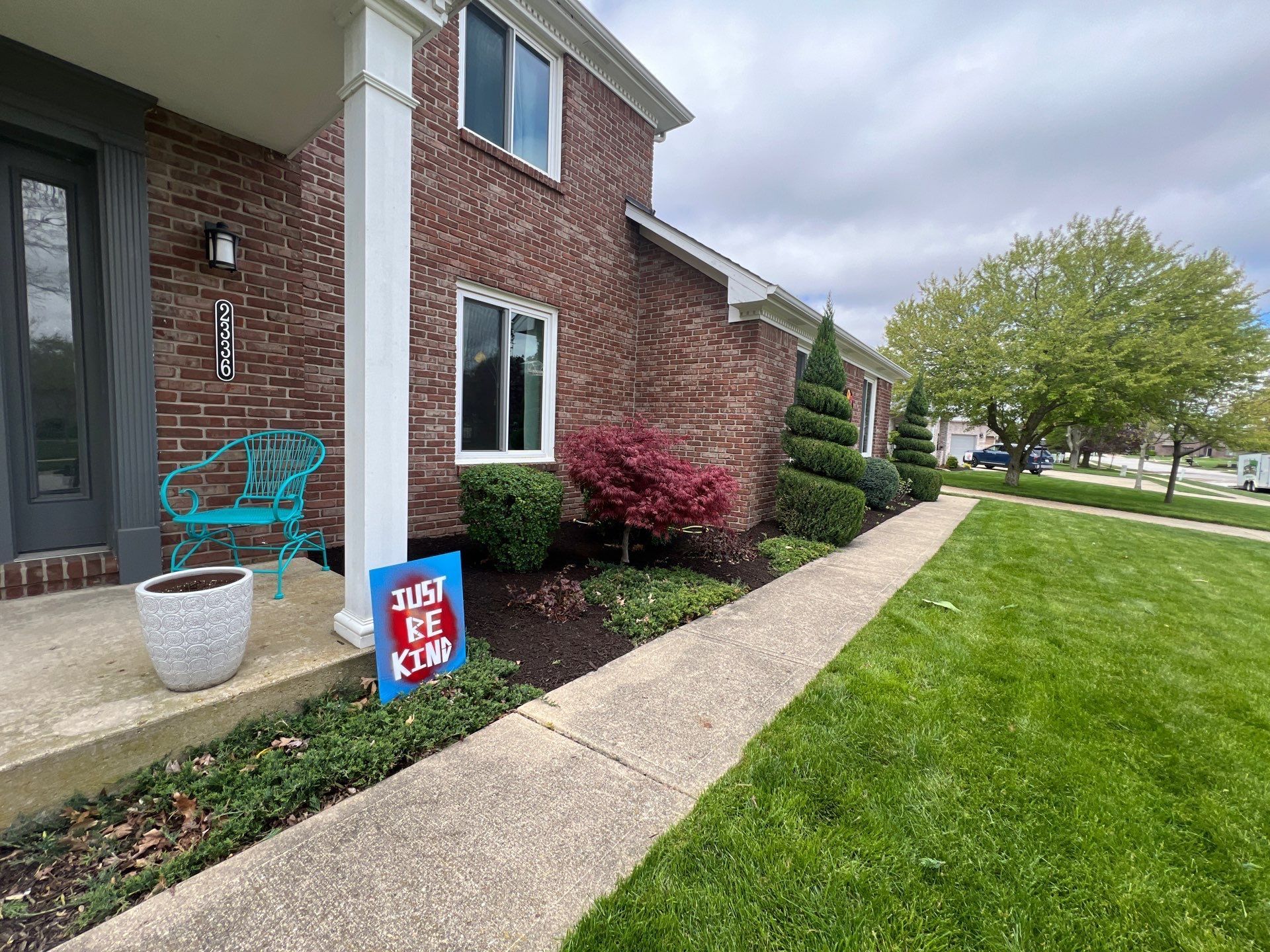 A brick house with a blue sign on the sidewalk in front of it.