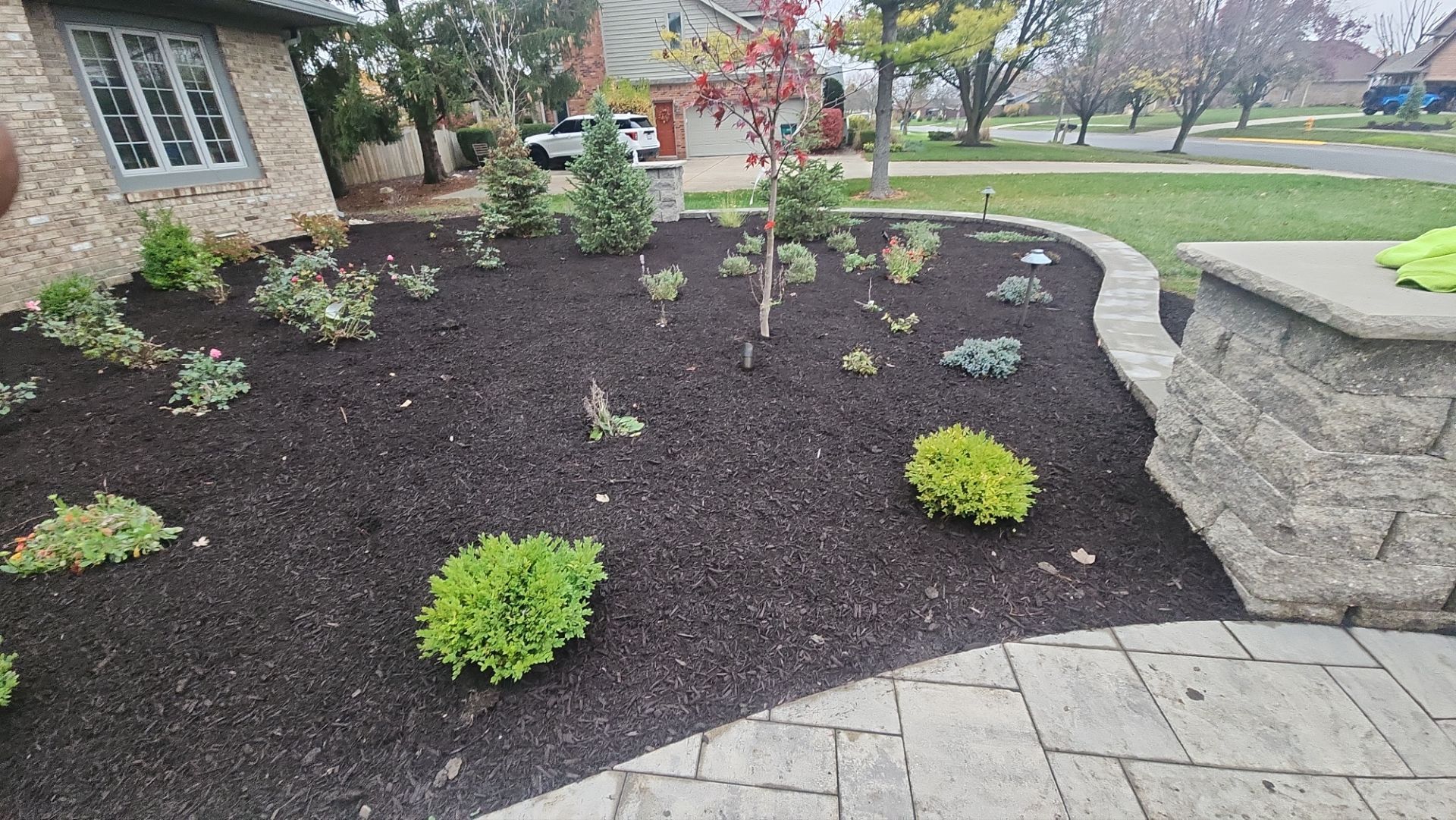 A brick walkway leading to a house with a garden in front of it.