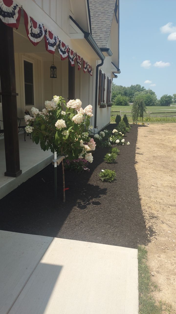 A white house with a porch and flowers in front of it