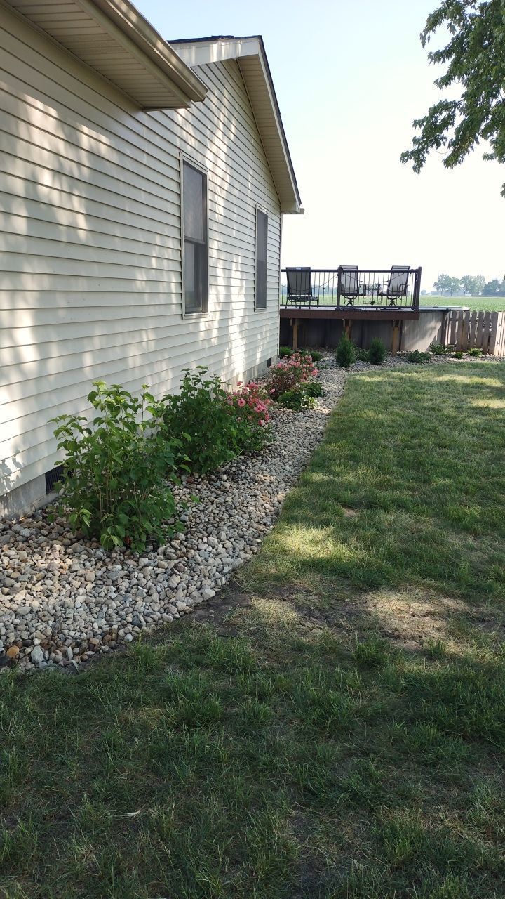 A white house with a large lawn in front of it and a deck.